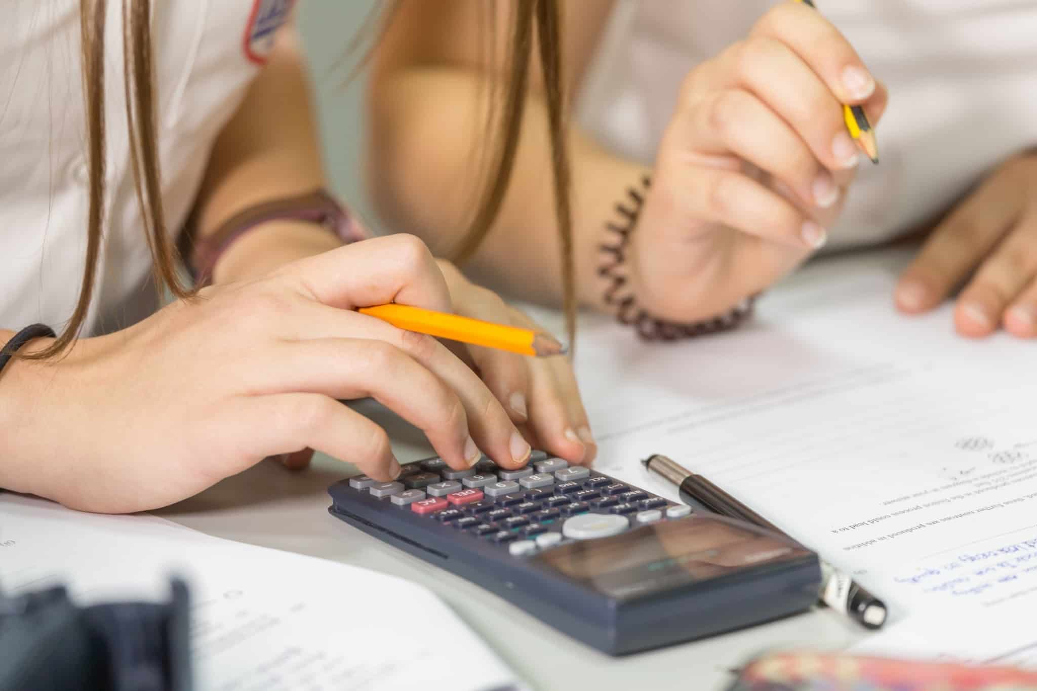 Imagem de duas pessoas a fazer contas numa calculadora - rever seguros