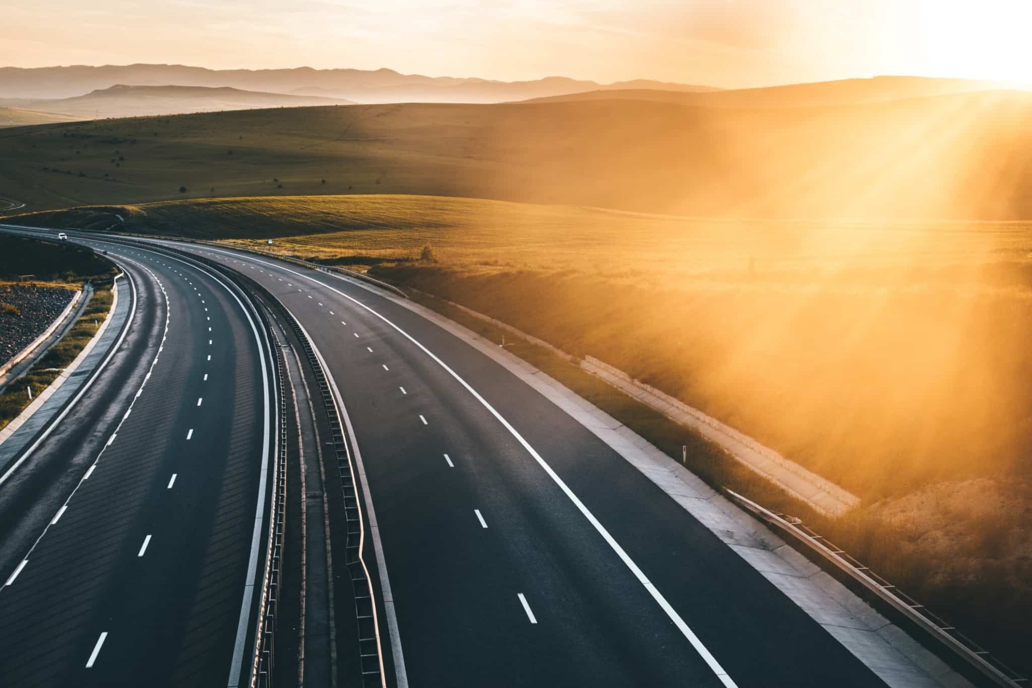 longa autoestrada, com visão nos dois sentidos, com um forte pôr do sol