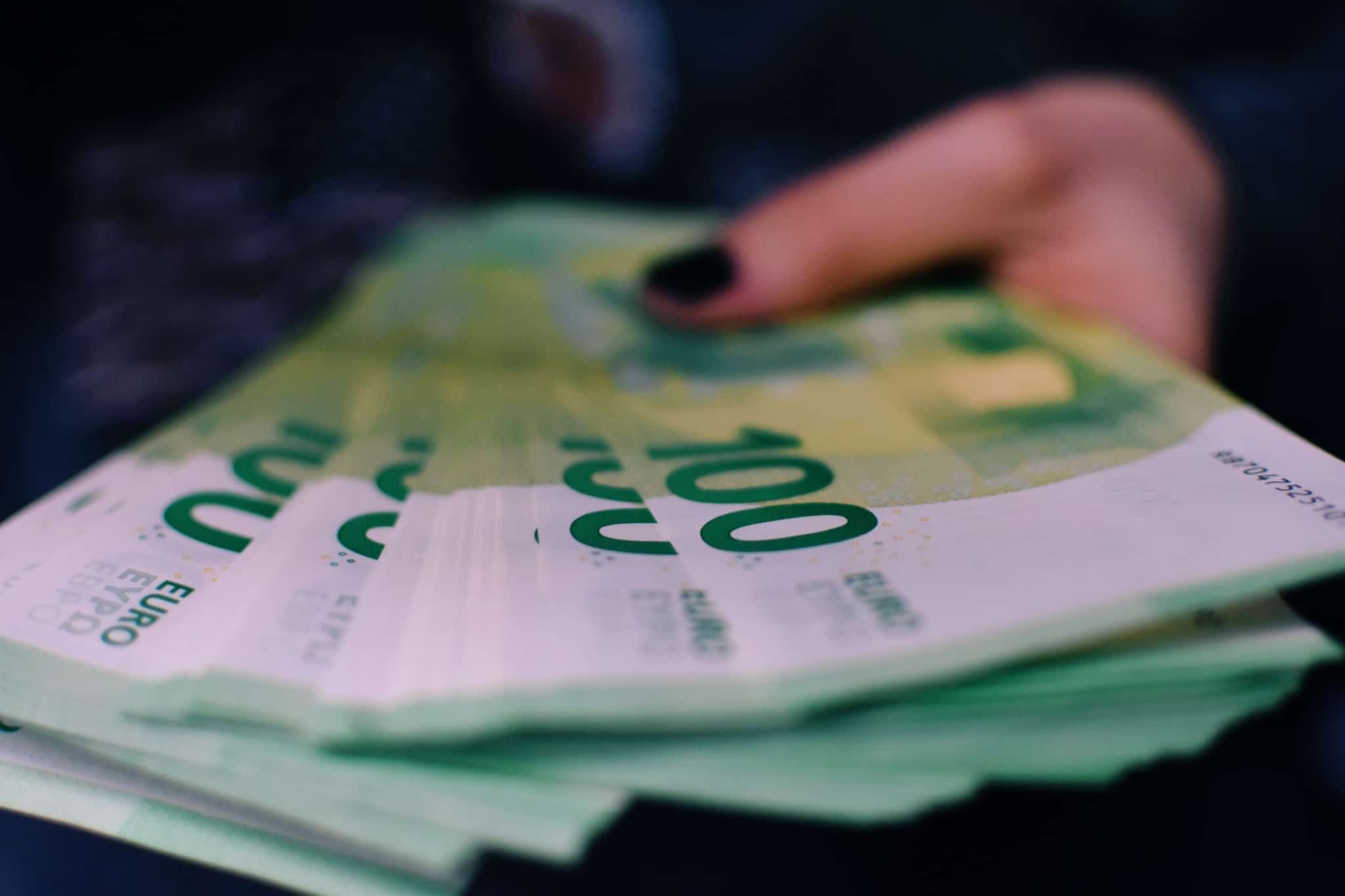 mão de uma jovem mulher segura um leque de notas de 100 euros a ilustrar 4 Coisas que não sabia que com as quais podia fazer dinheiro
