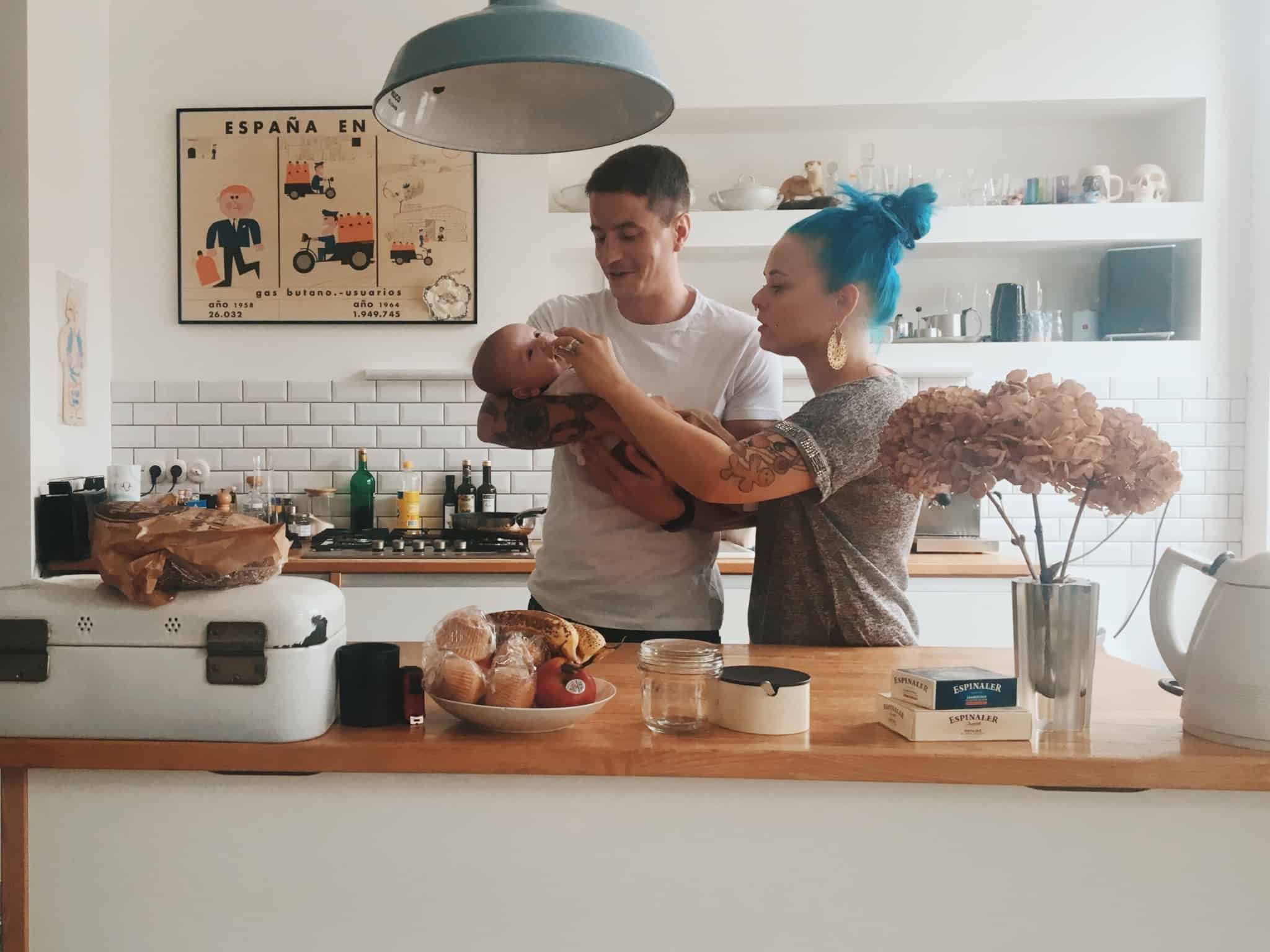 jovem casal segura bebé, em casa, na cozinha, muito felizes