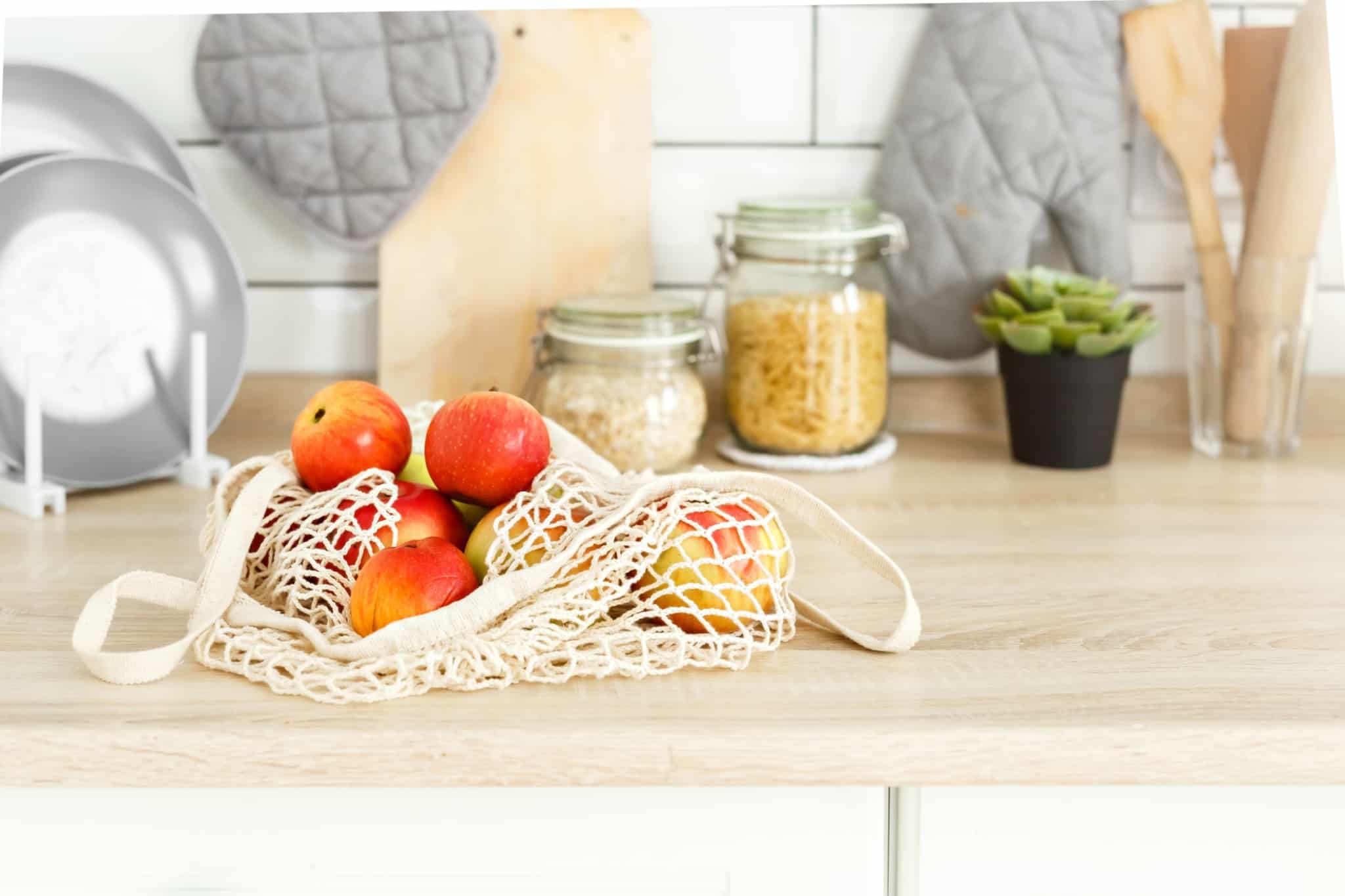 balcão da cozinha com frutas em saco reutilizável e em fundo vários produtos alimentares comprados a granel