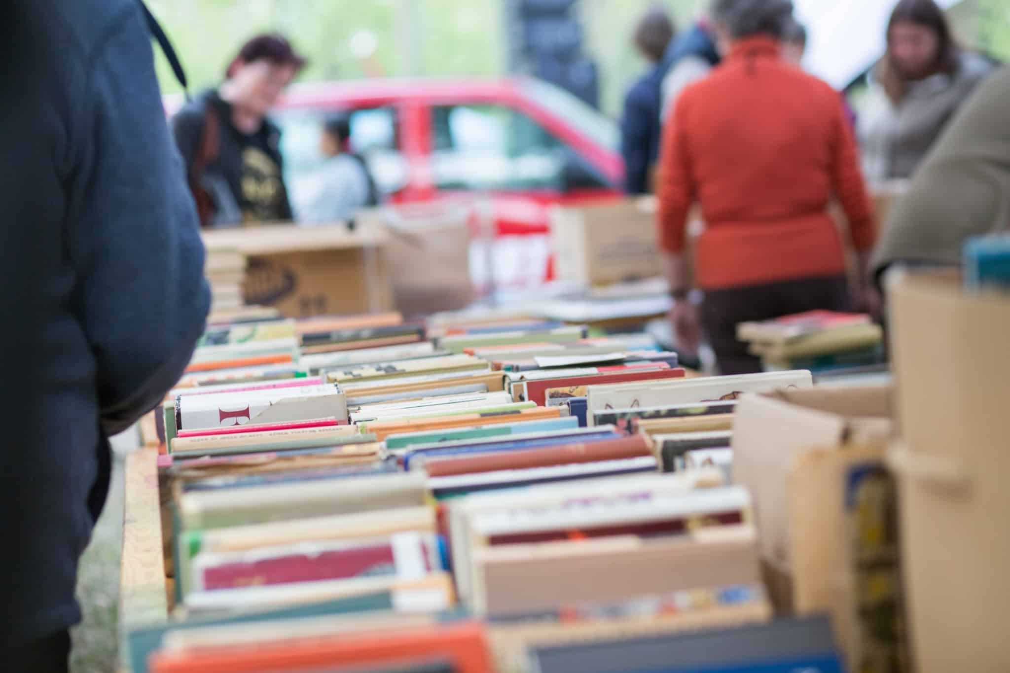 banca de livros usados em feira, com pessoas a consultar livros