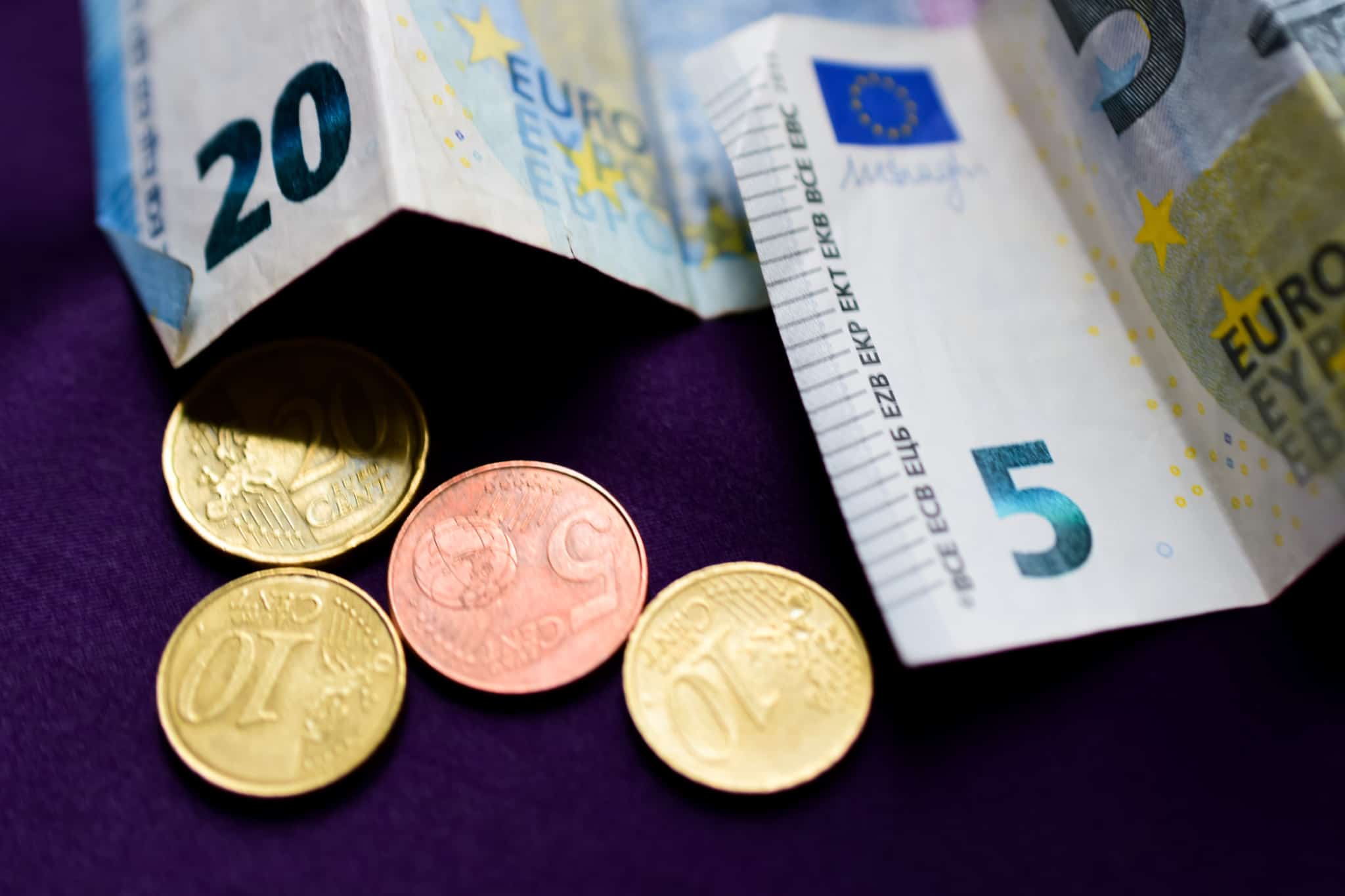 nota de 20 euros e de 5 euros mais umas moedas de euro em cima de uma mesa. Negociar o salário pode representar uns euros extra