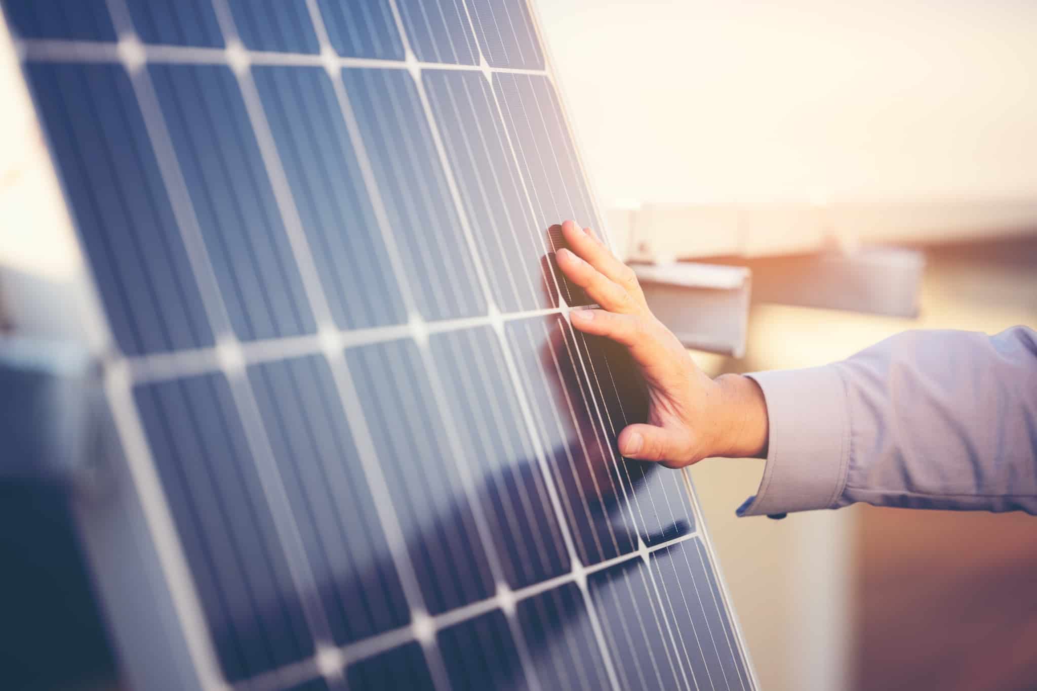 mão de um homem jovem toca num painel solar