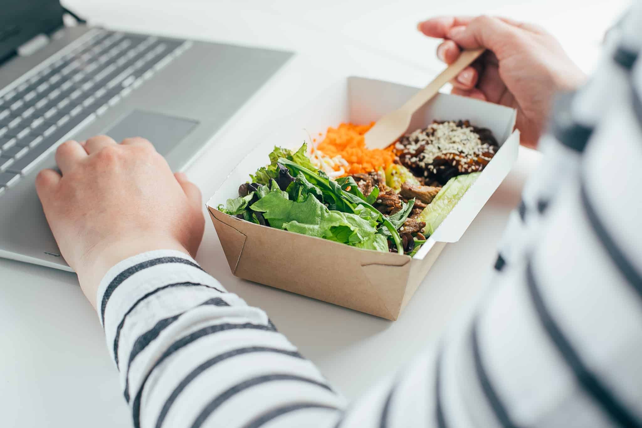 jovem mulher almoço frente ao computador, uma refeição leve