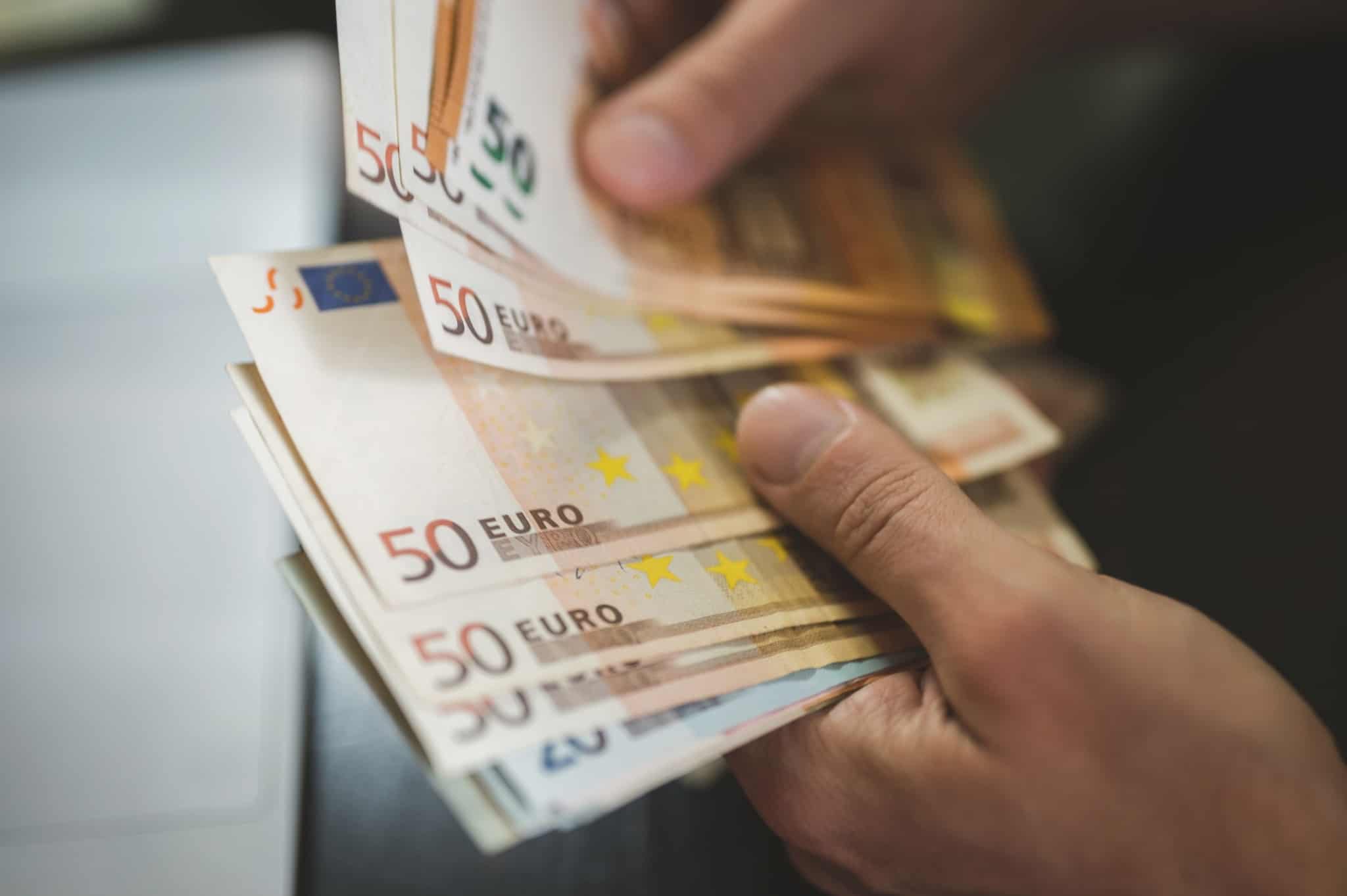 mãos de um jovem seguram notas de 50 e 20 euros