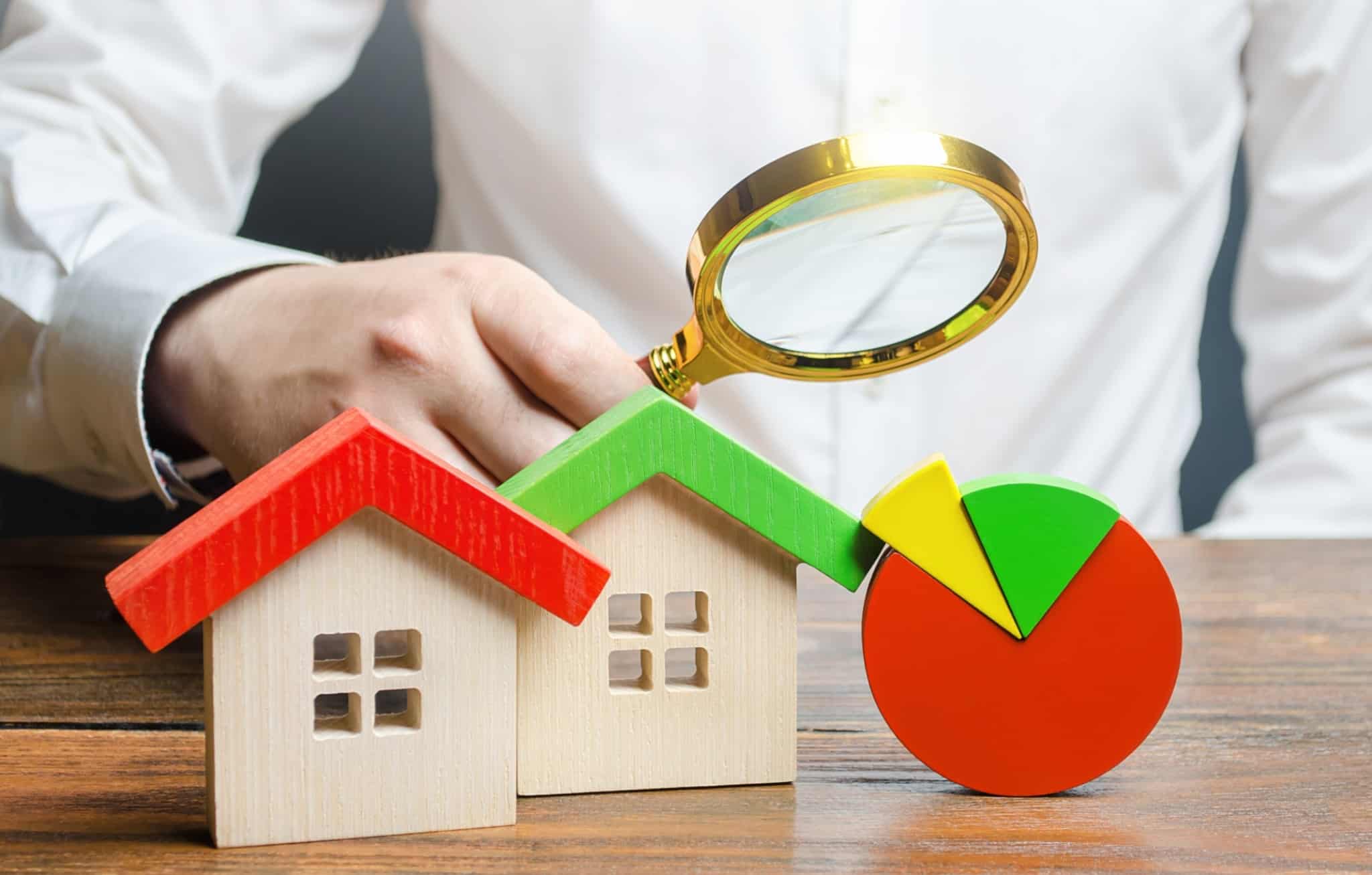 duas casas, um gráfico e um homem a segurar uma lupa