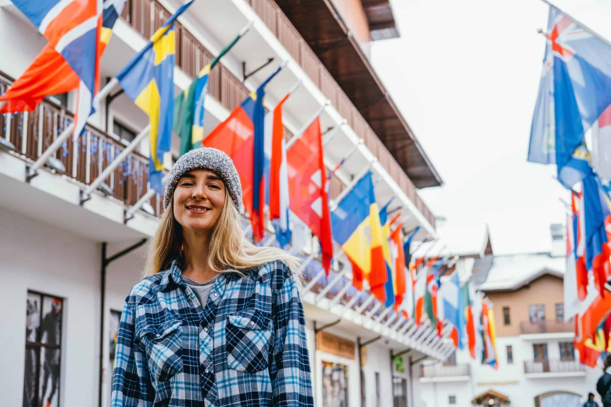 Foto de mulher em frente a várias bandeiras de países a evocar trabalho no estrangeiro e dupla tributação