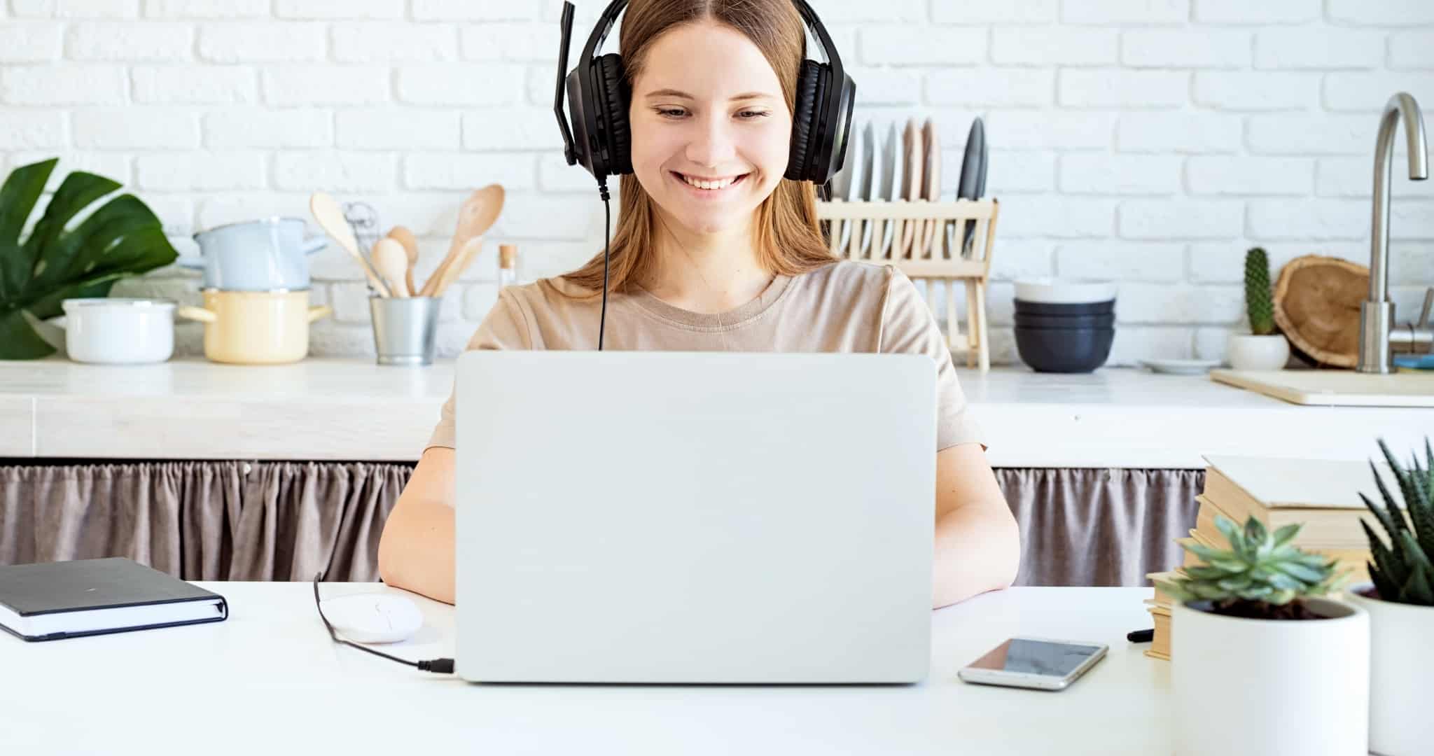 Jovem menor de idade sentada a um computador com fones a trabalhar