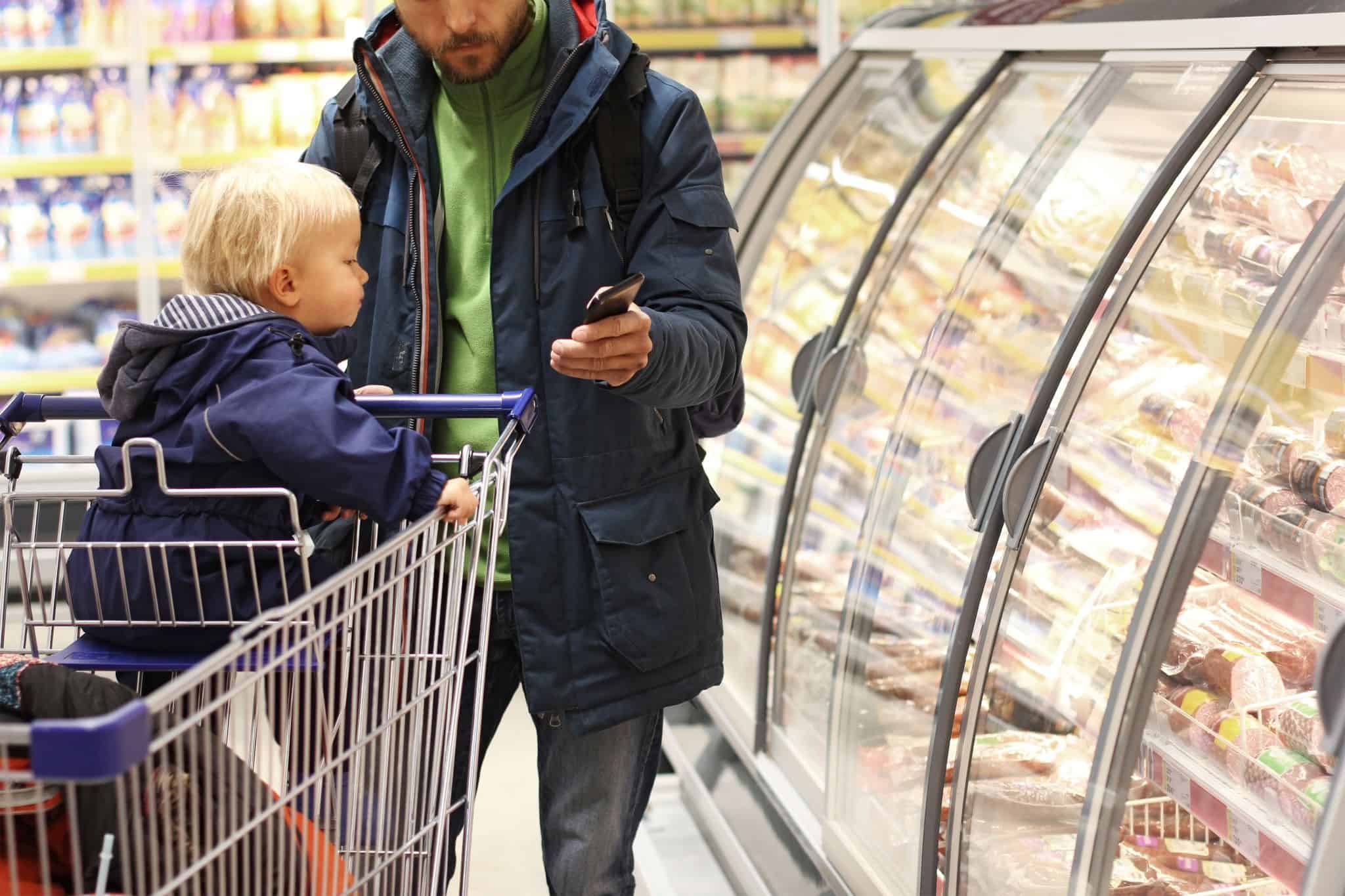 Homem com criança no supermercado faz contas à subida de preços