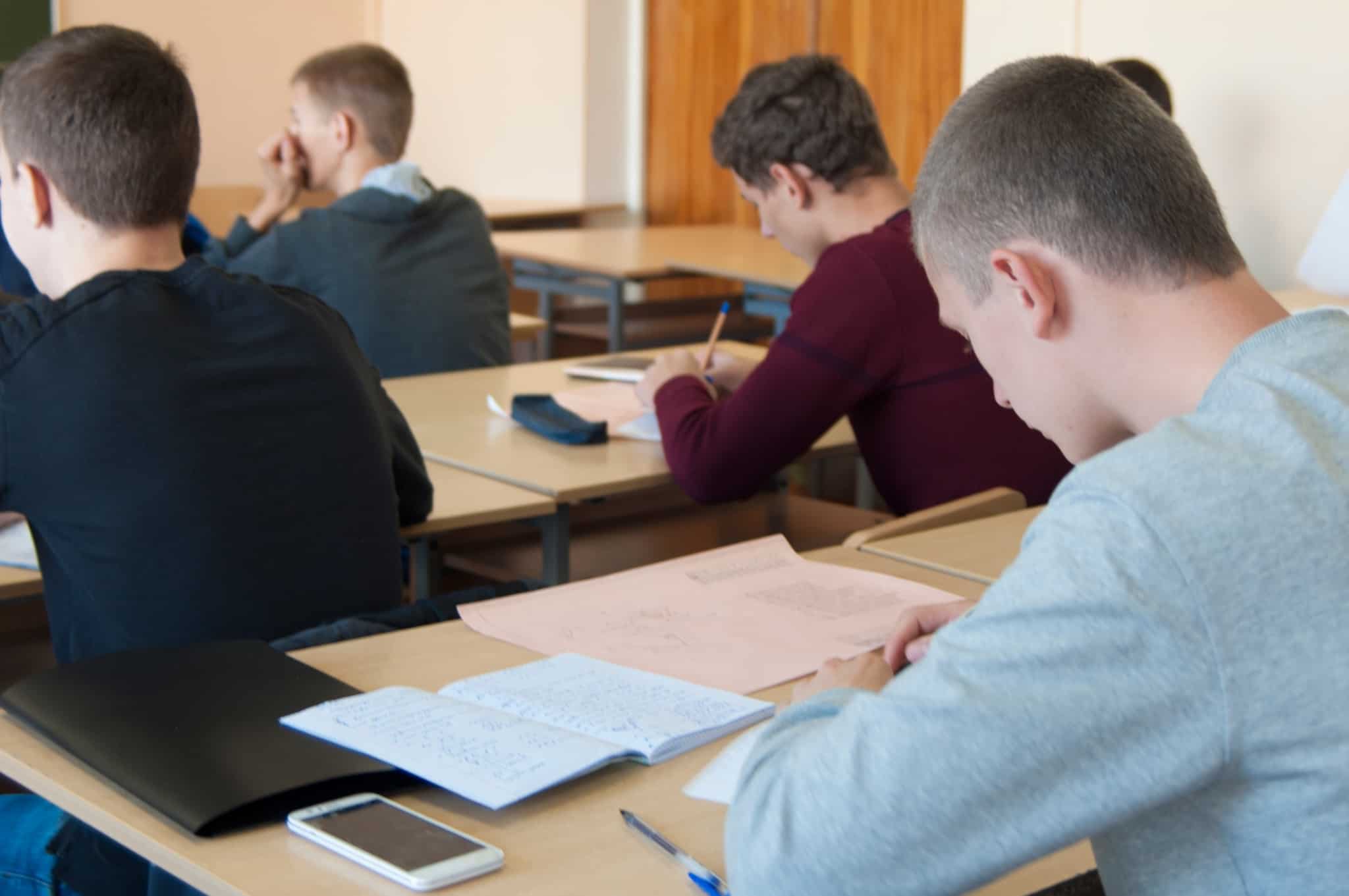 Estudantes sentados em mesas numa sala de aula