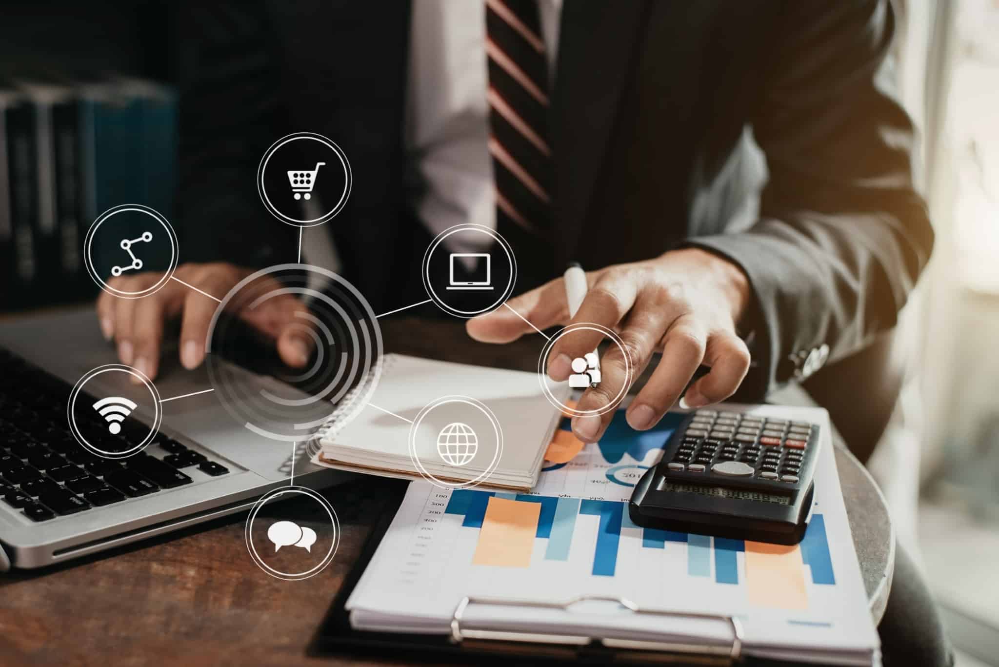 homem, no escritório, faz contas com apoio de calculadora e consultando documentos para fazer transferência via homebanking