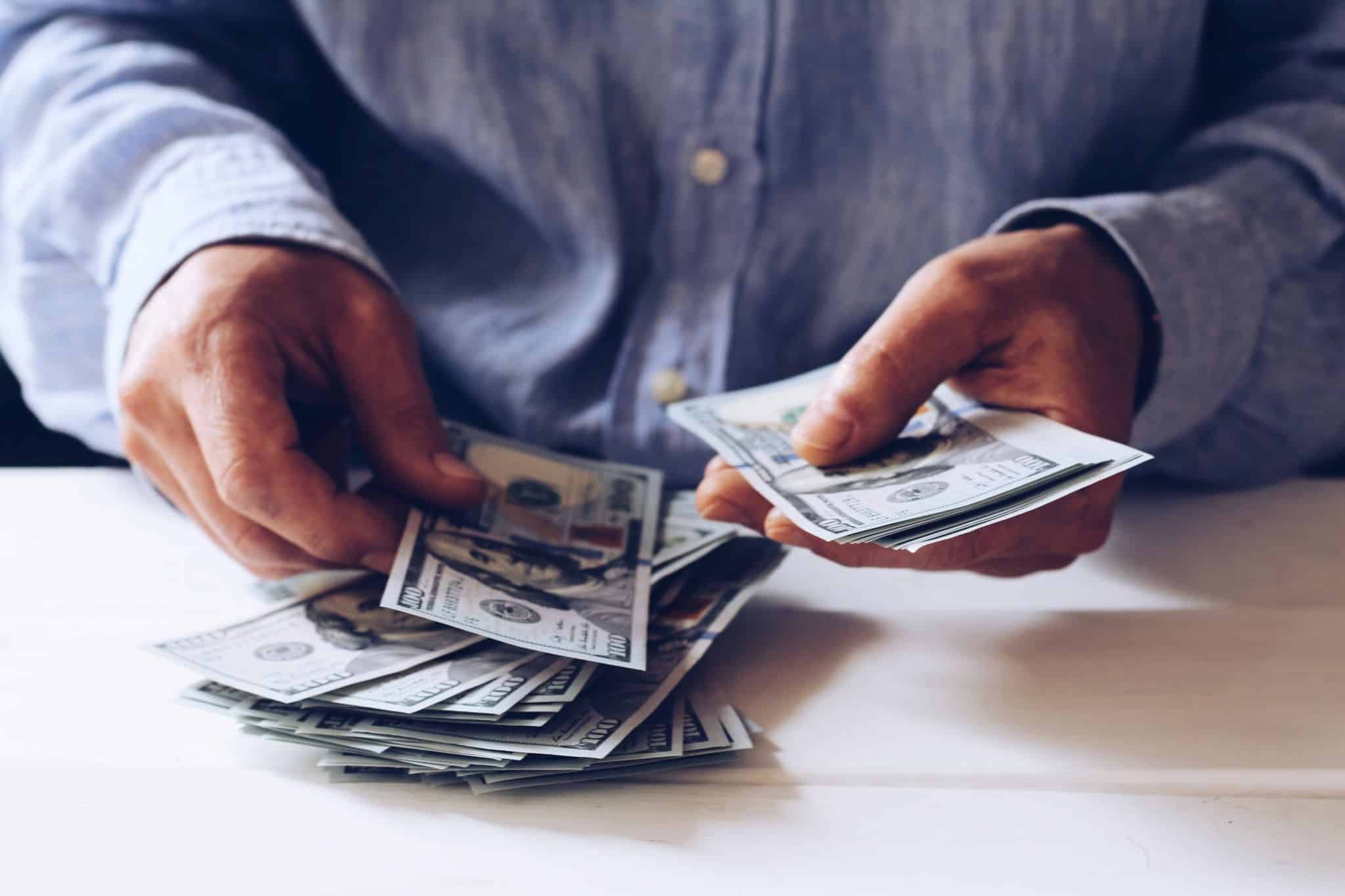 Imagem de alguém a contar notas de dólar à mesa - numa alusão aos rendimentos obtidos no estrangeiro para efeitos de irs