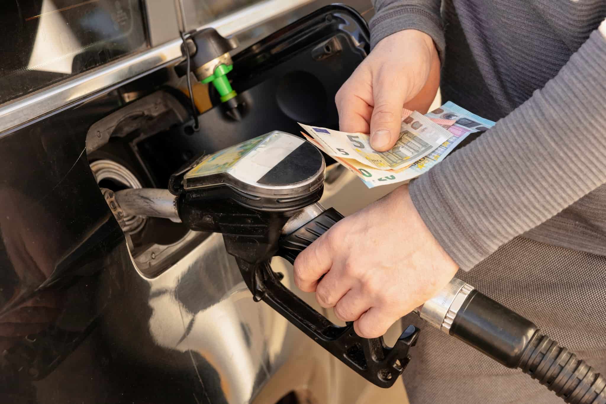 homem abastece carro já com algumas notas de euro na mão, preparado para pagar mais face ao aumento dos combustíveis