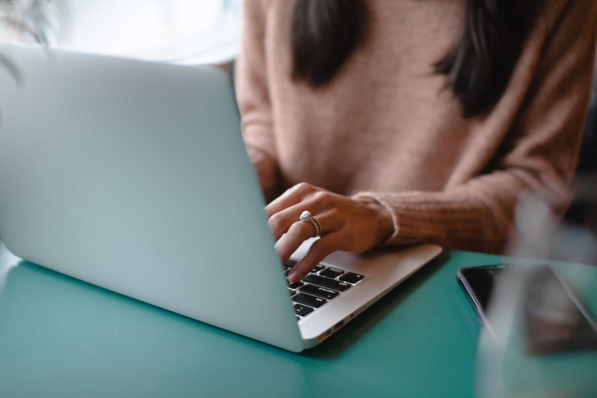 Jovem mulher sentada à mesa num computador a preencher IRS Jovem