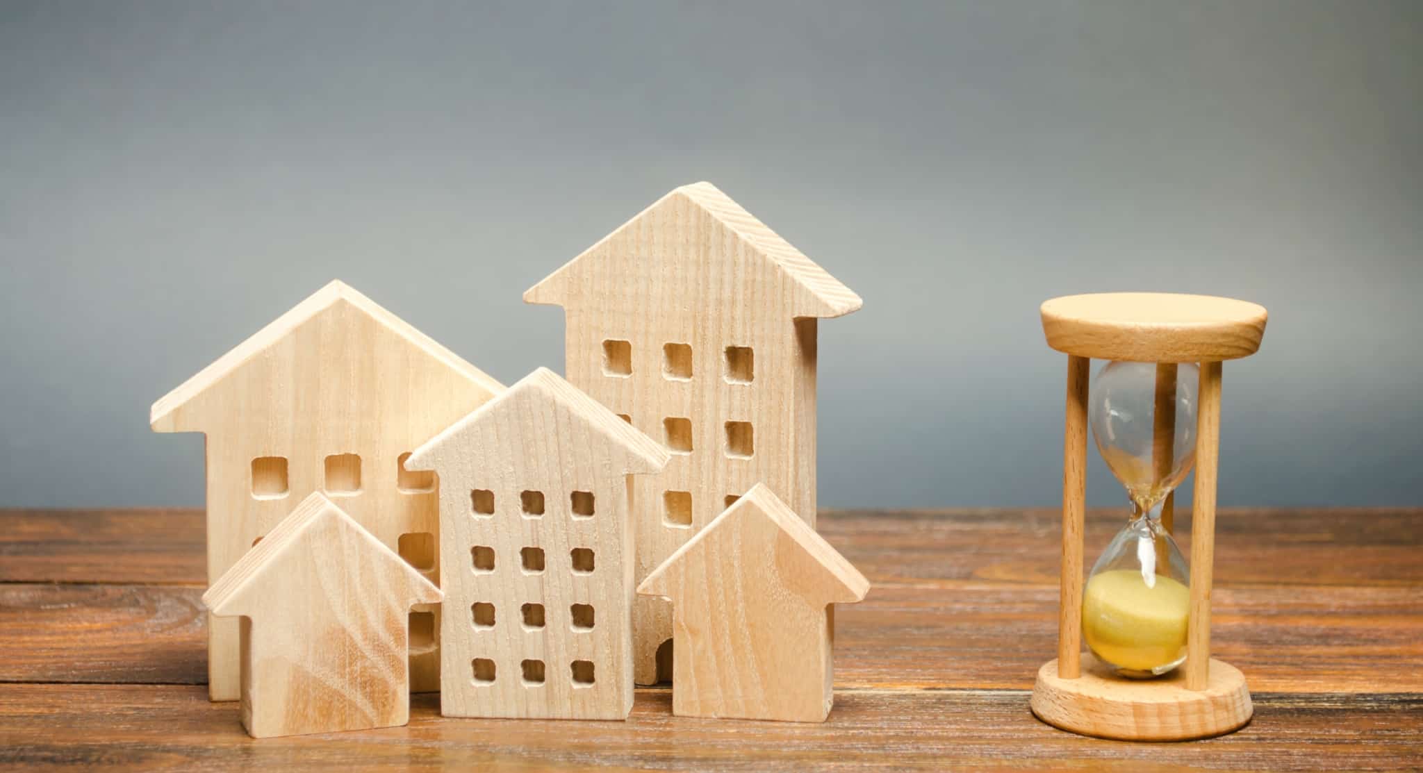 casas de madeira e uma ampulheta sobre a mesa a representar os novos prazos do crédito habitação