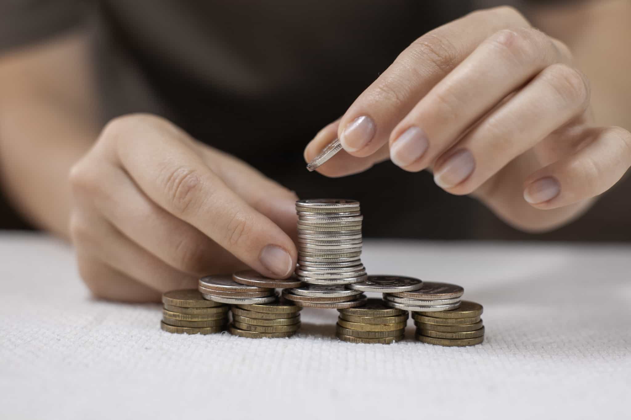 várias pilhas de moedas com diferentes alturas a serem construídas poelsa máos de uma jovem simbolizando a idade para fazer um PPR
