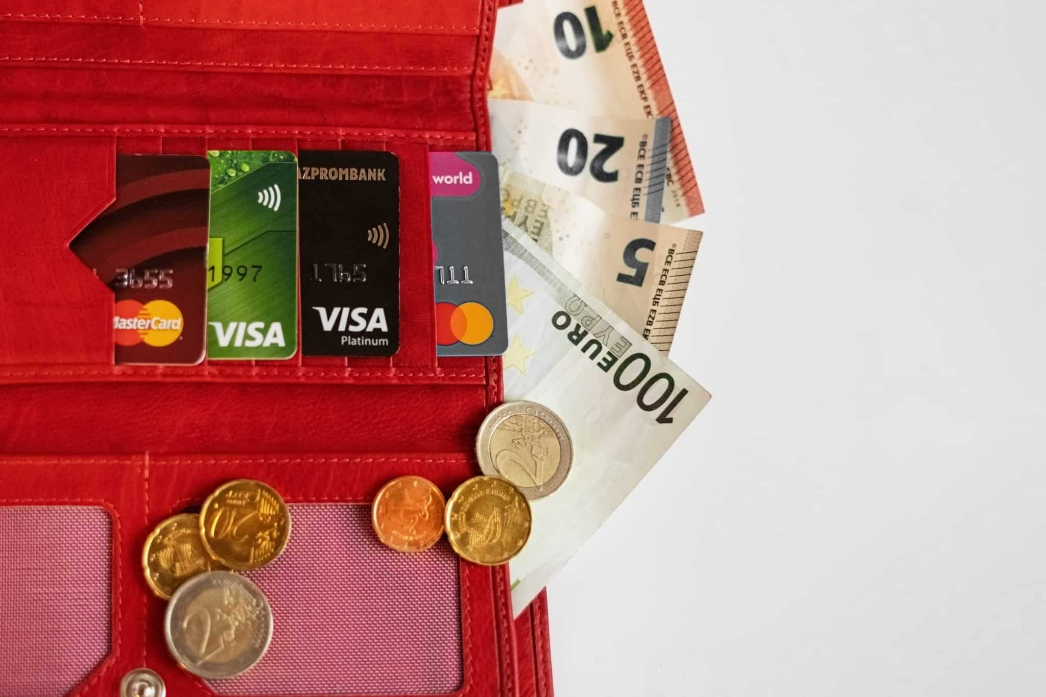 liquidar a dívida de cartão de crédito, com vários exemplares destes cartões arrumados na lateral de uma carteira vermelha, de pele, que guarda ainda algumas notas de euro e moedas