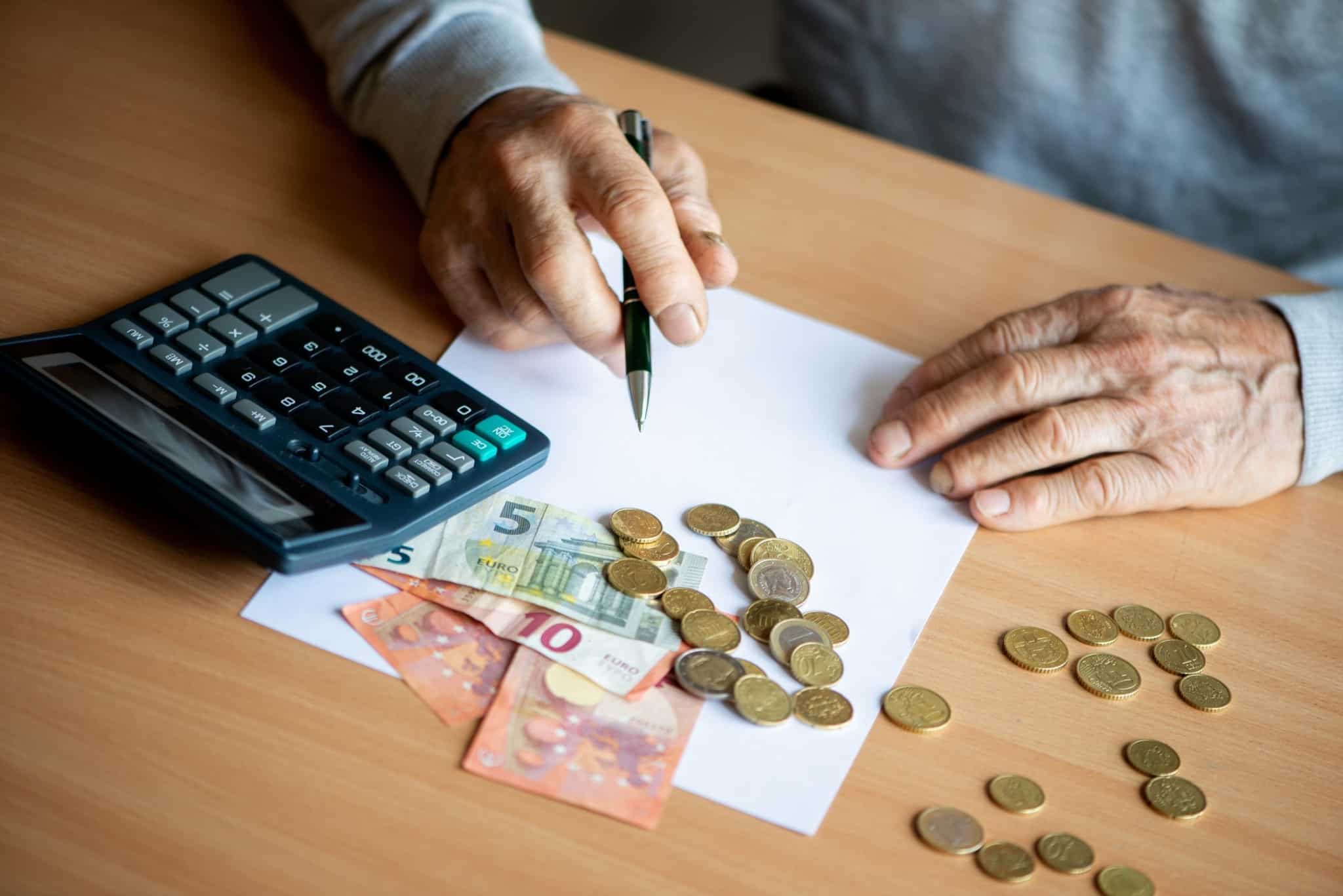 produção fotográfica mostra uma mesa com moedas e notas de Euro e as mãos de um idoso , enquanto este faz as contas no papel e com o apoio de uma calculadora, aos aumentos de pensões até 1108 euros