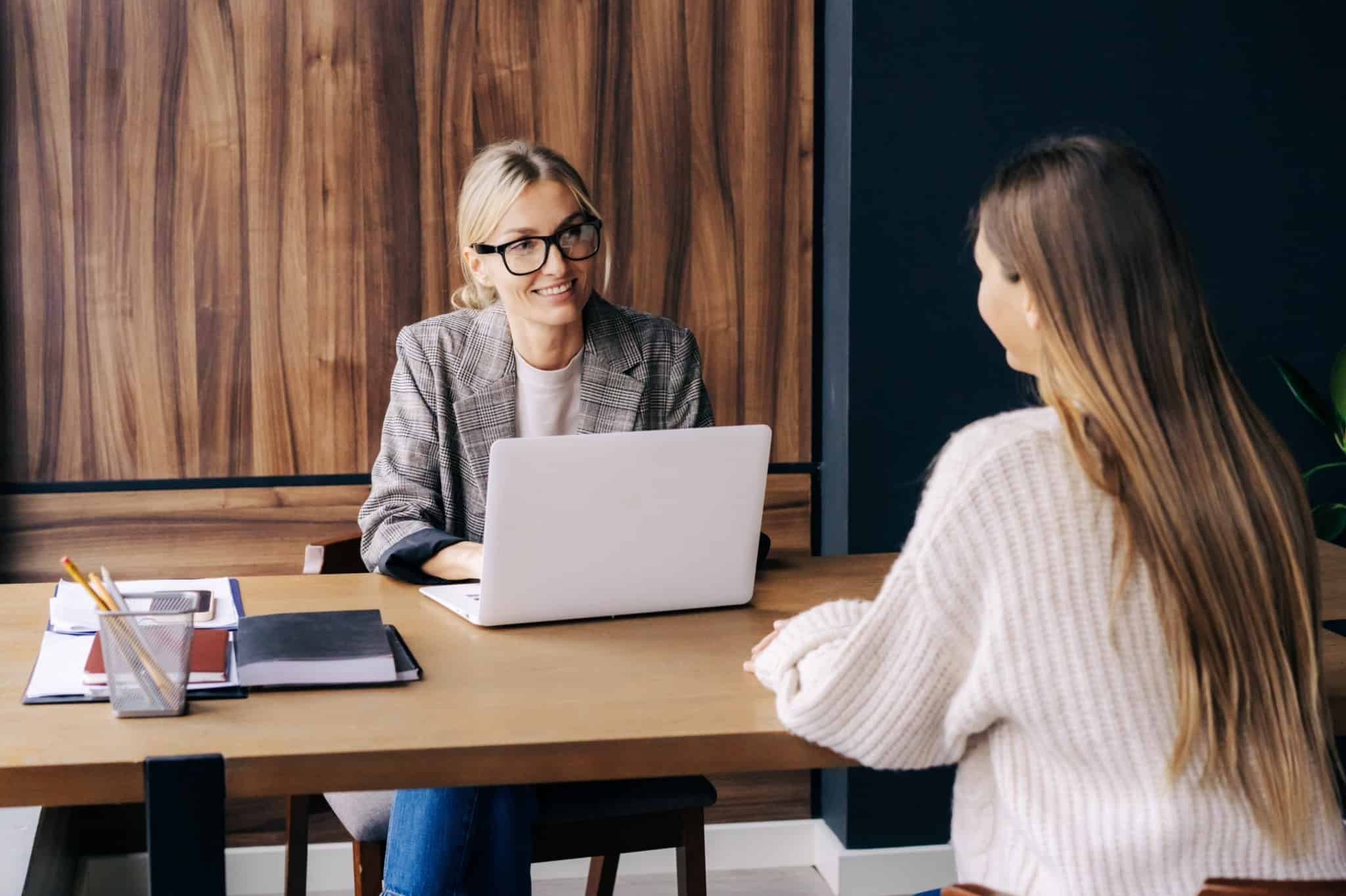 Entrevista de emprego. Mulher tenta recrutar uma jovem, apresentando os benefícios disponíveis