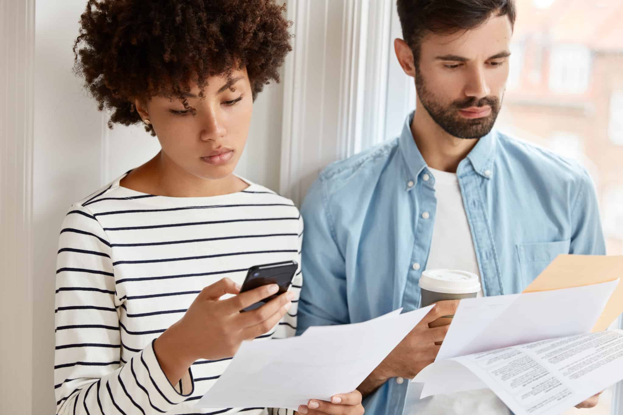 jovem casal estuda documentos e faz contas para decidir como investir o reembolso do IRS