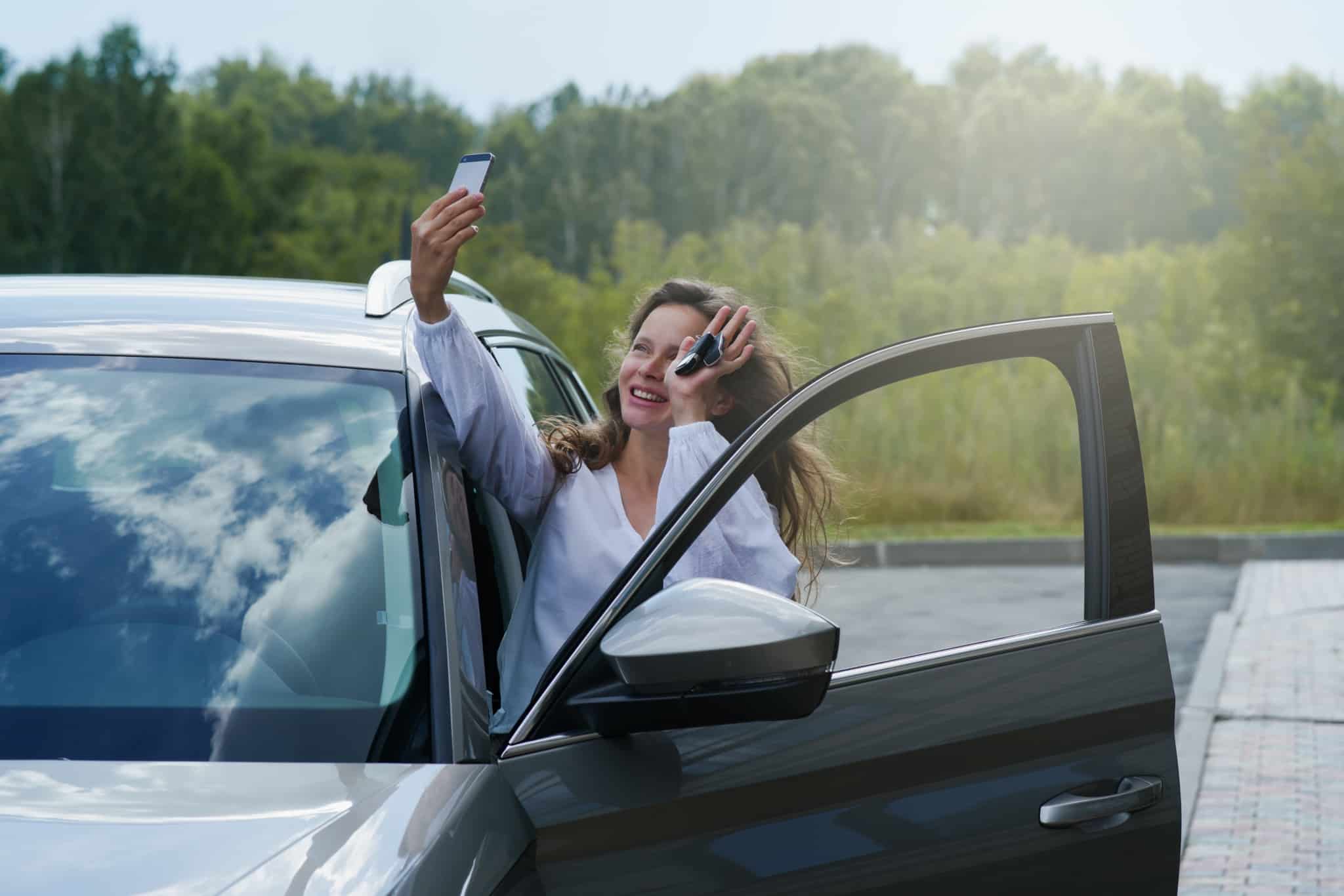 jovem mulher, depois de algum tempo a pensar em comprar carro, decidiu avançar e está feliz a fazer uma video chamada enquanto entra no veículo e mostra a chaves do seu carro novo