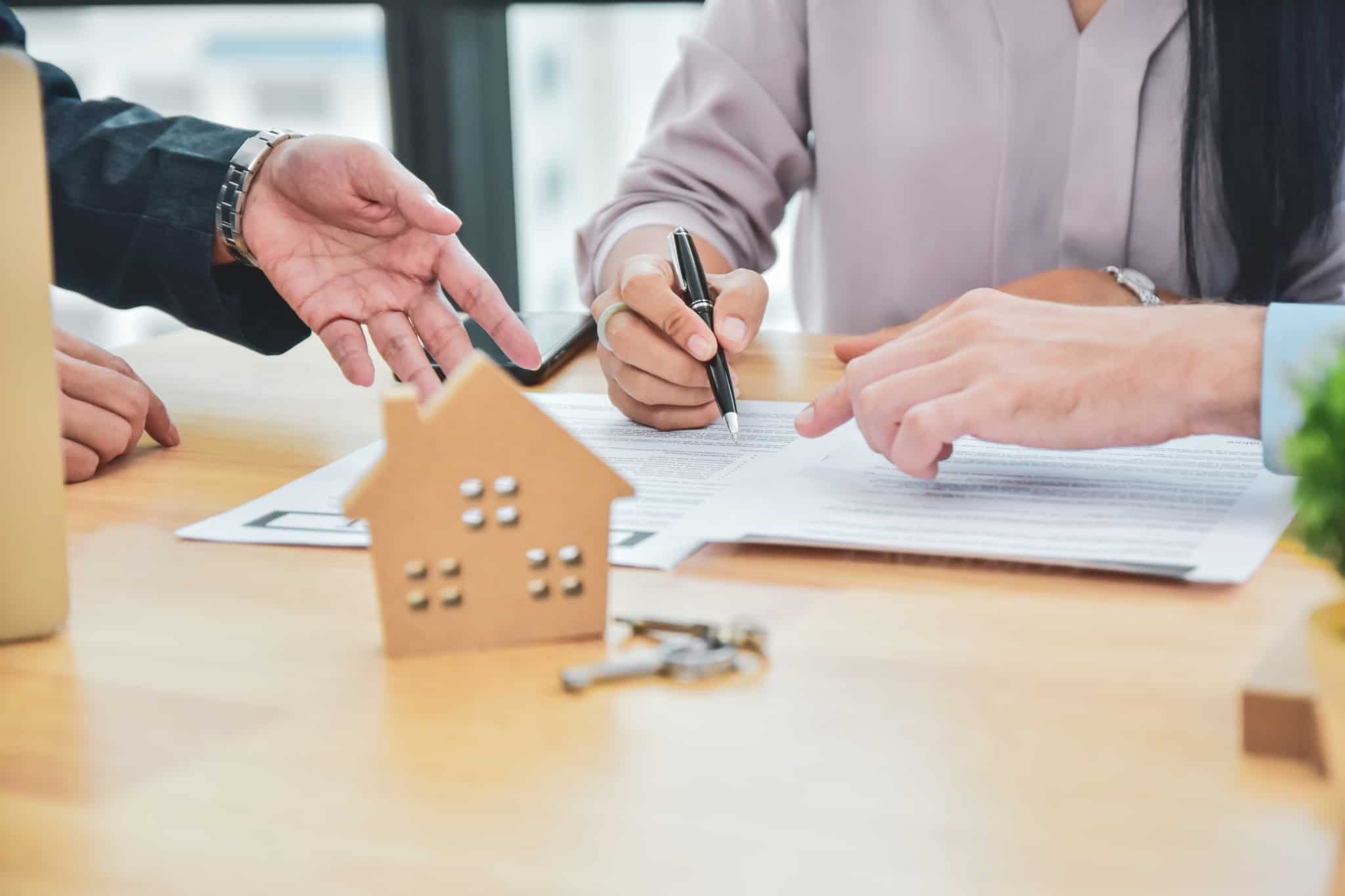 assinatura de um contrato de arrendamento, com uma mão a assinar e outra a indicar o que preencher no documento onde constam também direitos e deveres do arrendatário