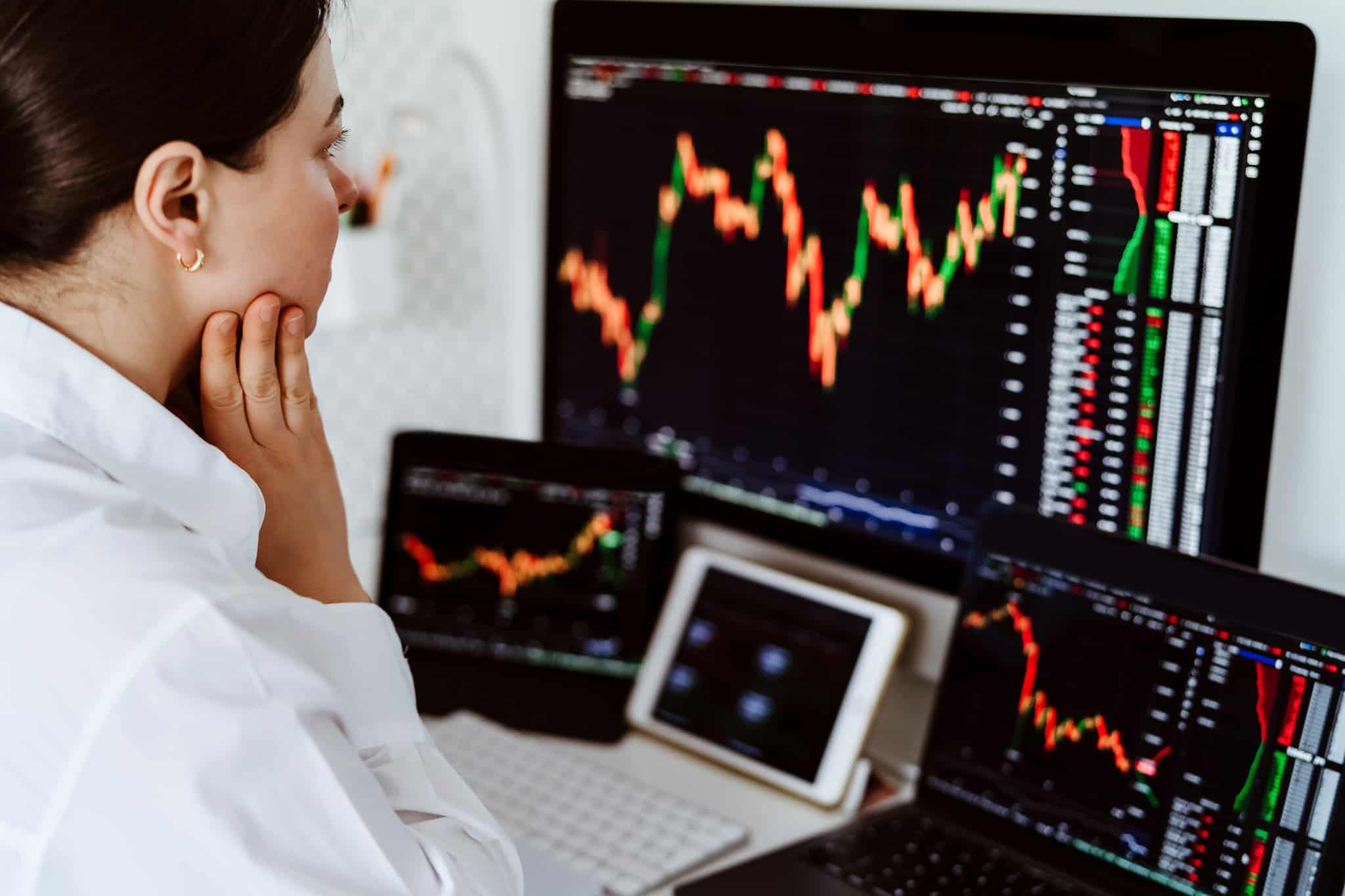 jovem mulher, especialista em mercados, analisa no ecran do seu computador os gráficos de ações de empresas que pagam dividendos