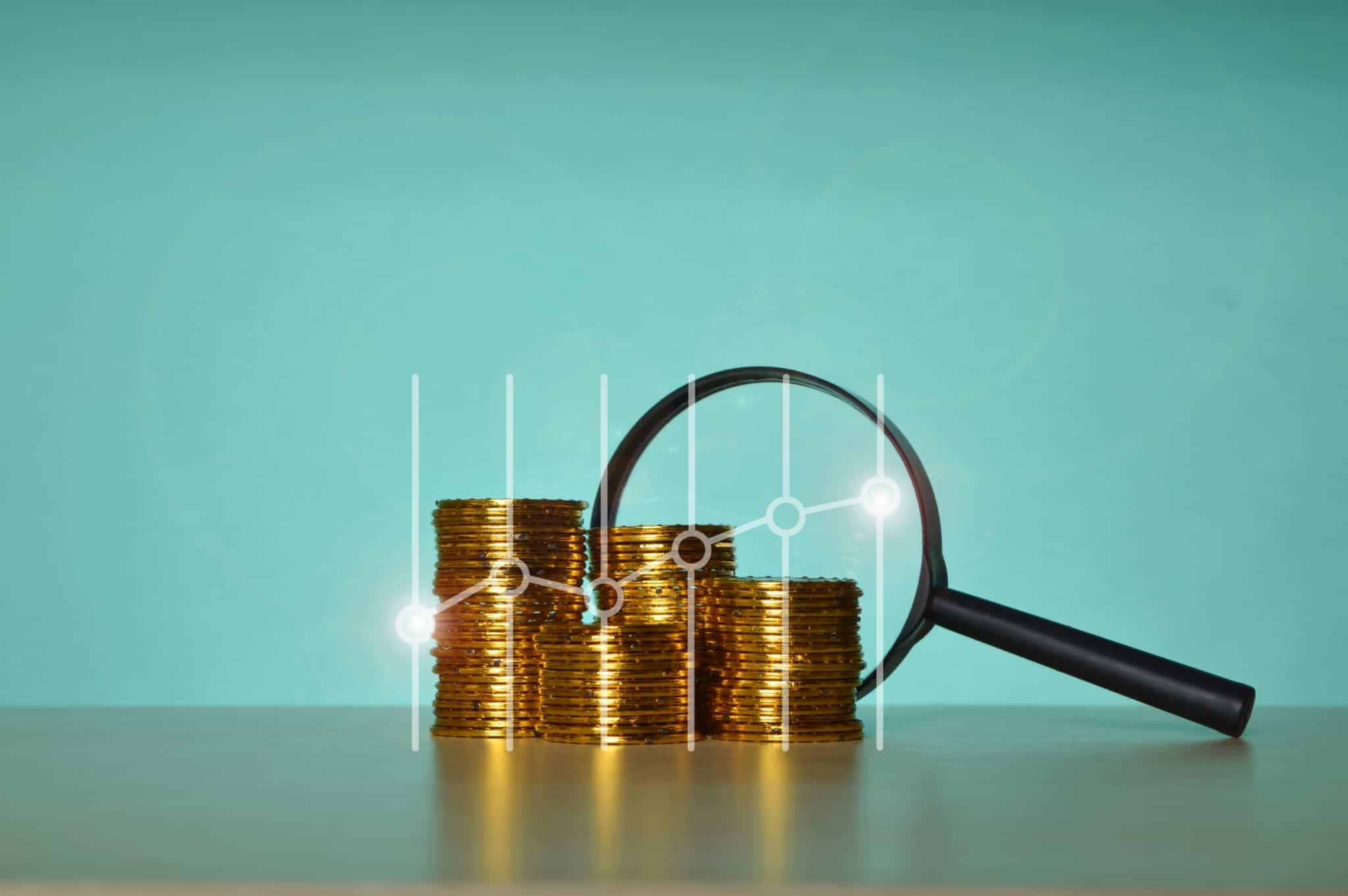 produção fotográfica ilustra o tema inflação, investimentos, poupança com um fundo azul e três pequenas pilhas de moedas, em crescendoi, com uma lupa encostada