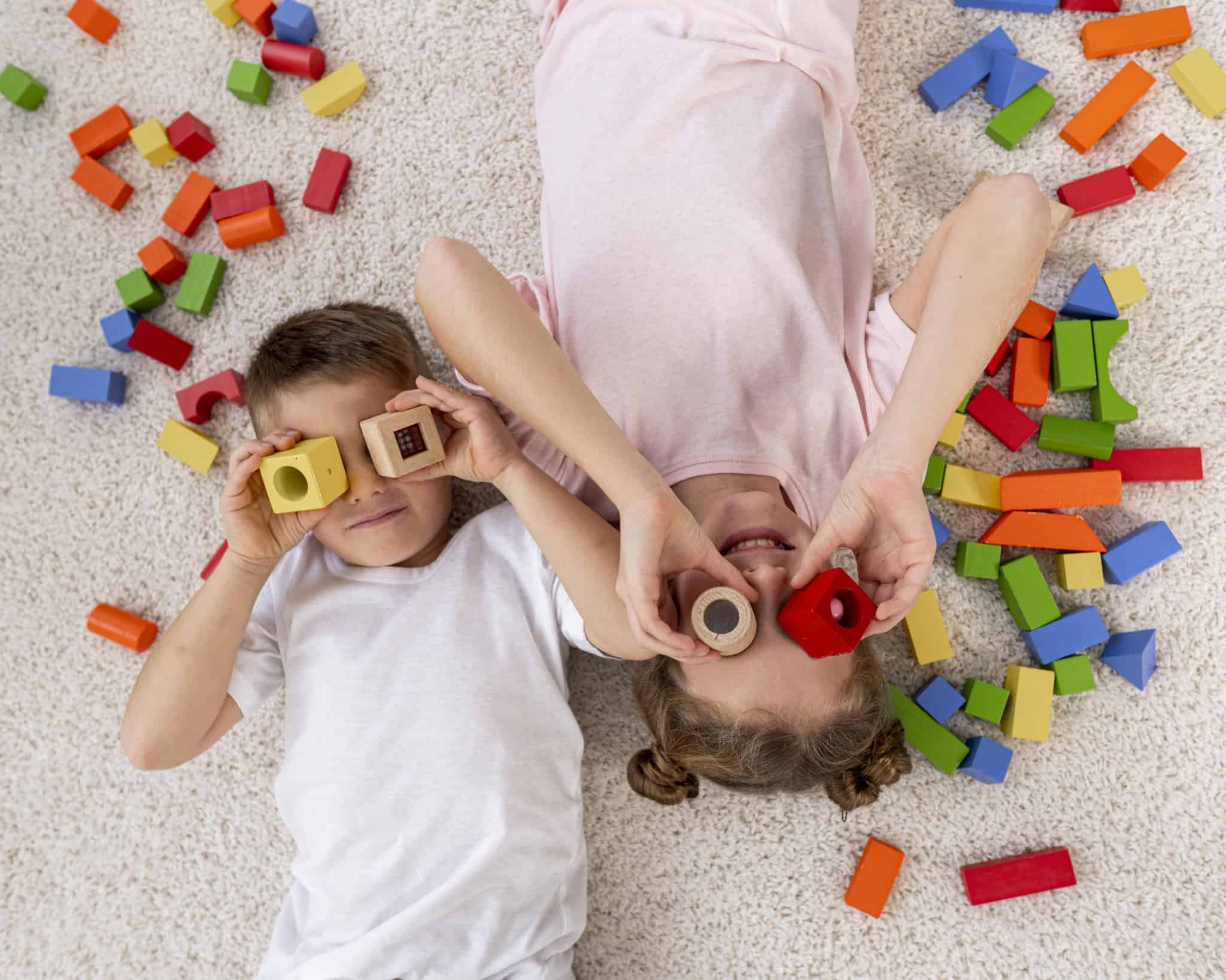 Crianças deitadas no chão a usar peças de lego como binóculos