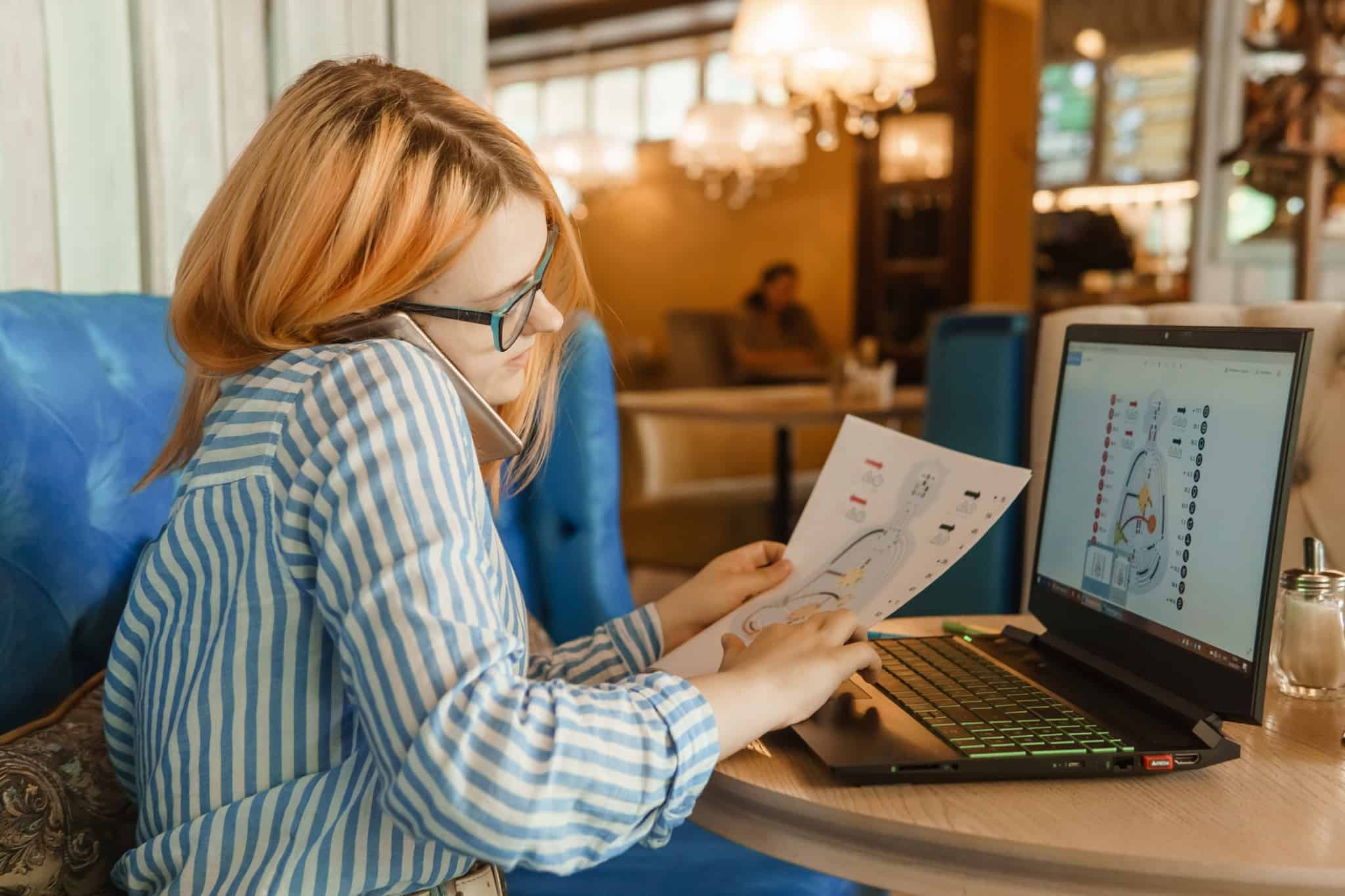 jovem mulher a estudar o corpo humano e a falar ao telemóvel enquanto estuda, tentando conciliar o trabalho e os estudos