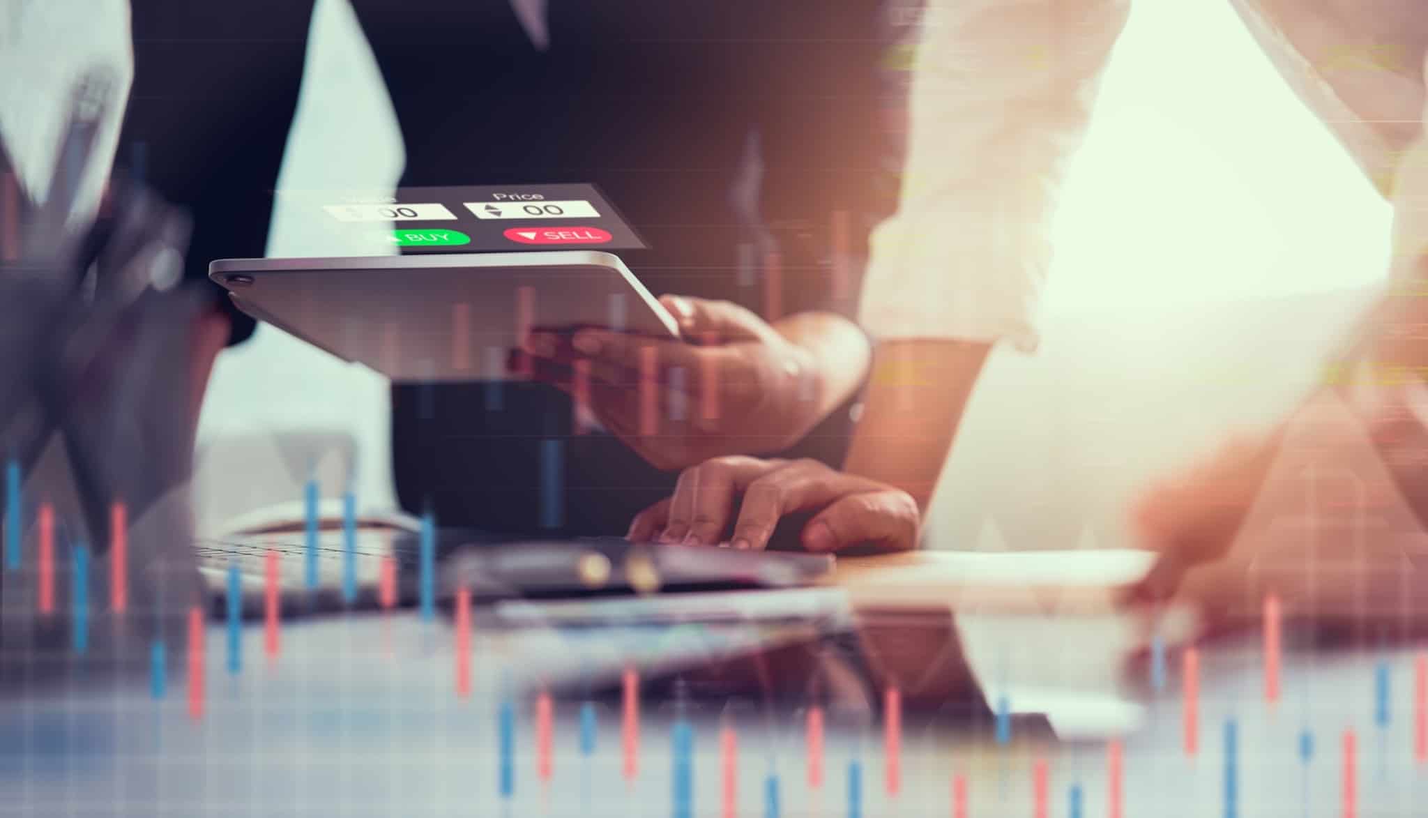 dois homens analisam evolução dos mercados financeiros , com gráficos e documentos digitais, estando ao serviço do regulador, ou seja, da CMVM