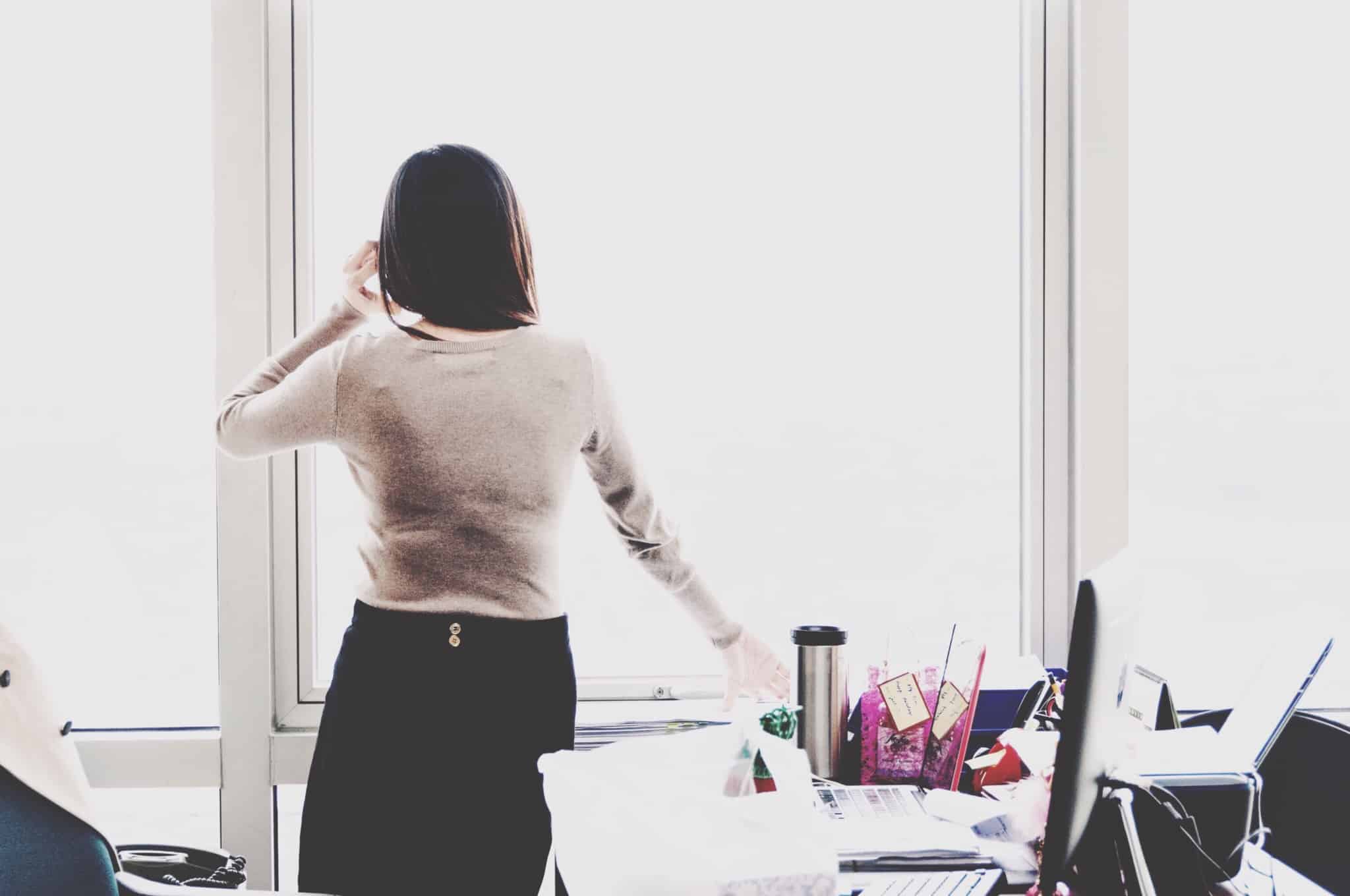 jovem miulher de costas, ao telemóvel, prepara-se para deixar o seu posto de trabalho e vai precisar de faltar ao trabalho uns dias