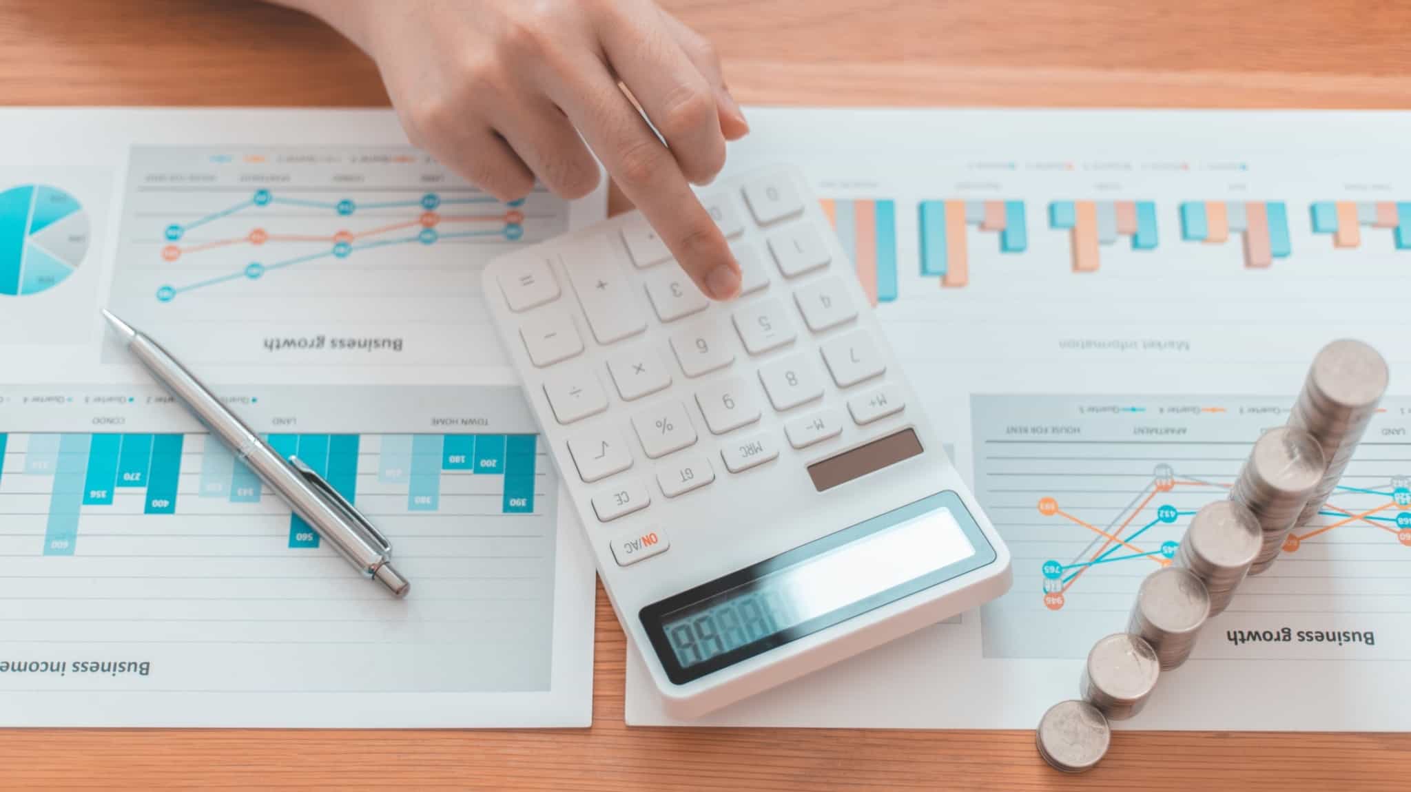 Investidor faz contas ao retorno dos seus investimentos recorrendo a uma máquina calculadora e a gráficos