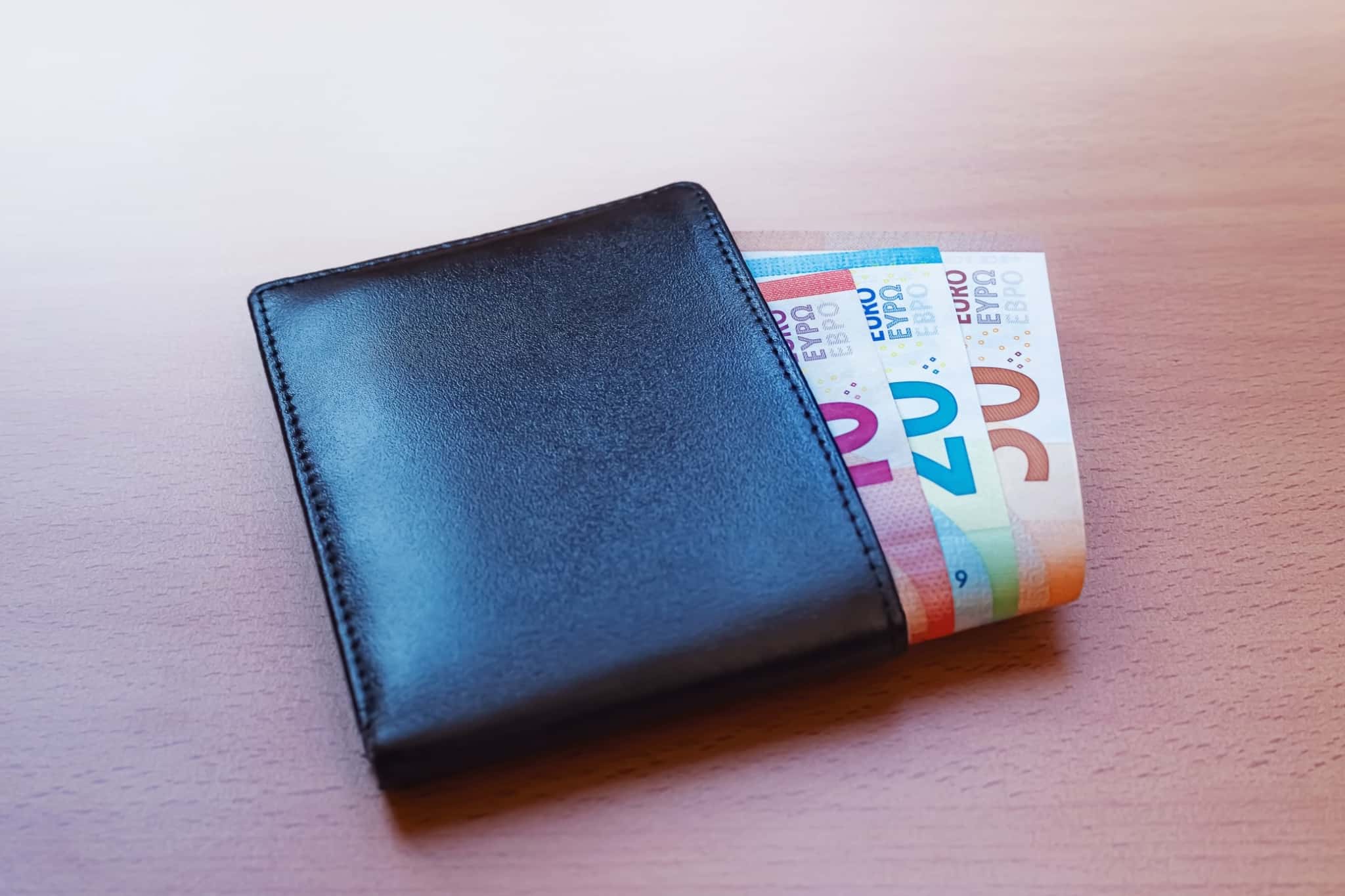 Notas de euro saem de uma carteira de pele preta