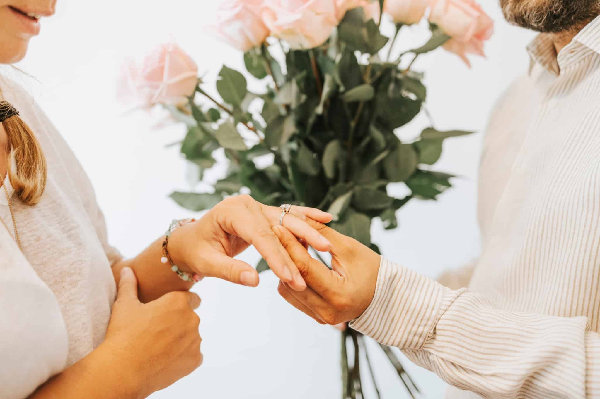 homem e mulher a trocar alianças no dia do casamento para depois pedir a certidão de casamento