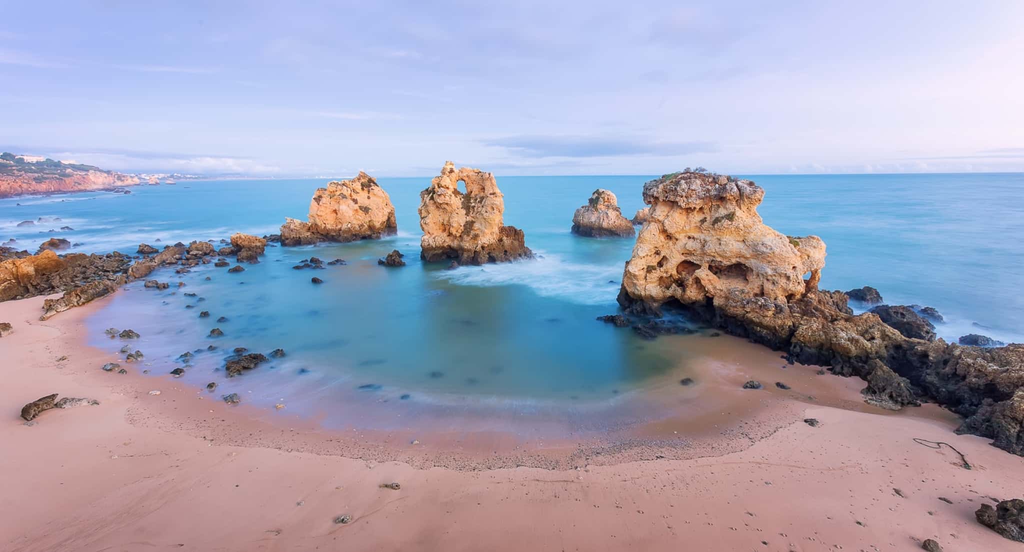 Pôr do Sol numa praia do Algarve, onde se vê o mar e alguma rochas