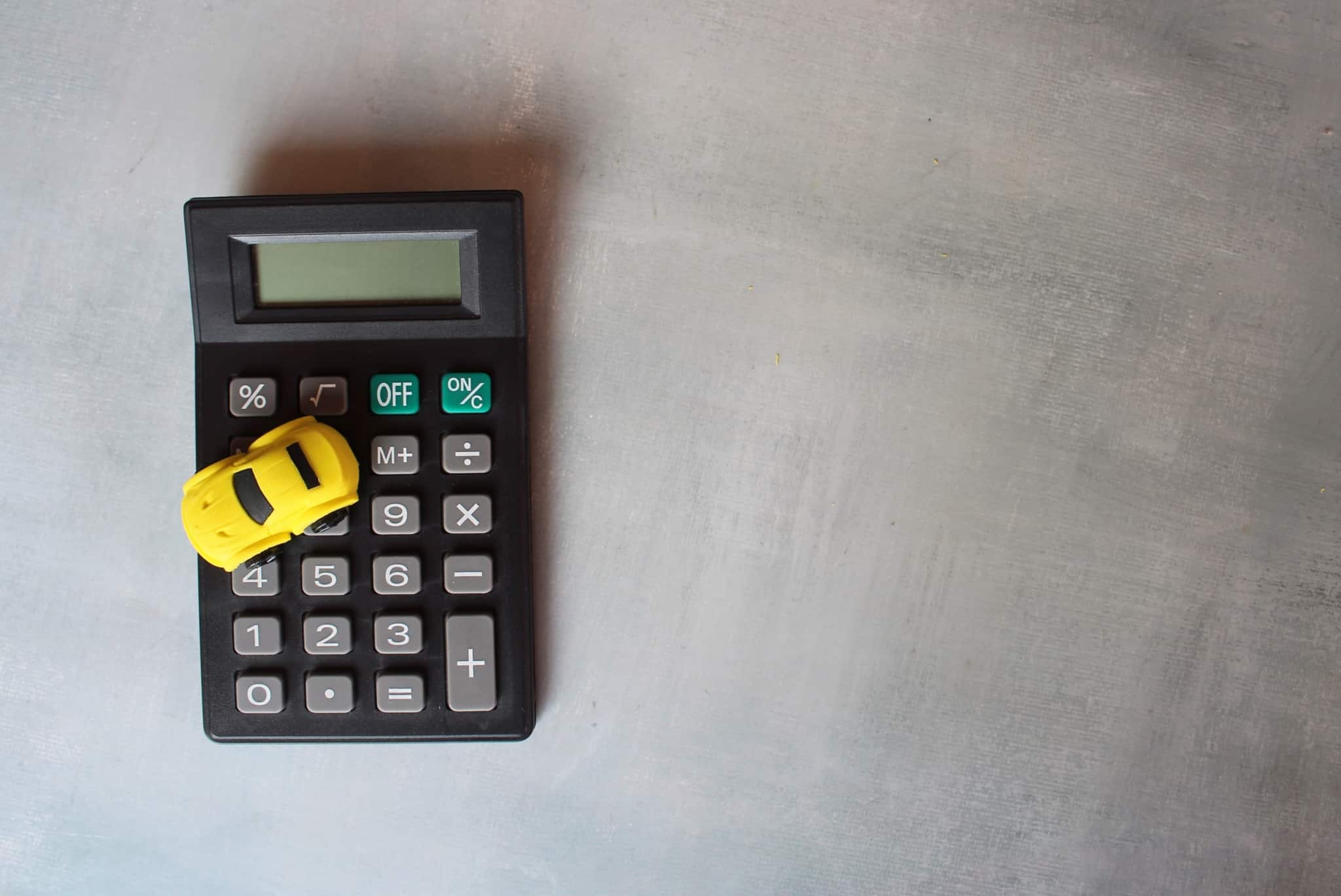 um carrinho em cima de uma calculadora a ilustrar se é possível obter um crédito para comprar casa quando se tem um crédito automóvel