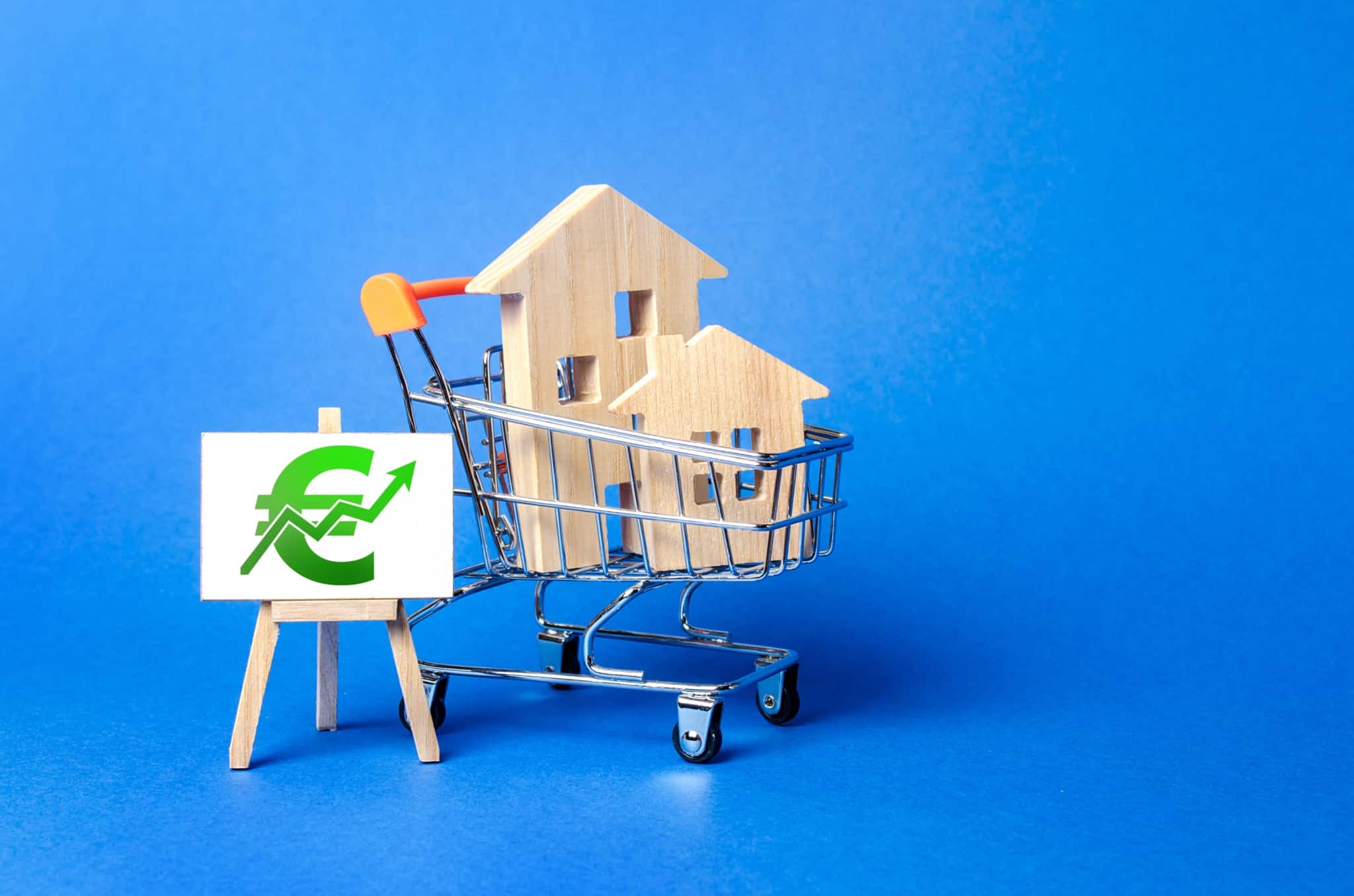 imagem com umas casas em madeira num carrinho de compras e o simboloo do euro com uma sete a subir a demonstrar a subida da Euribor e o aumento da inflação