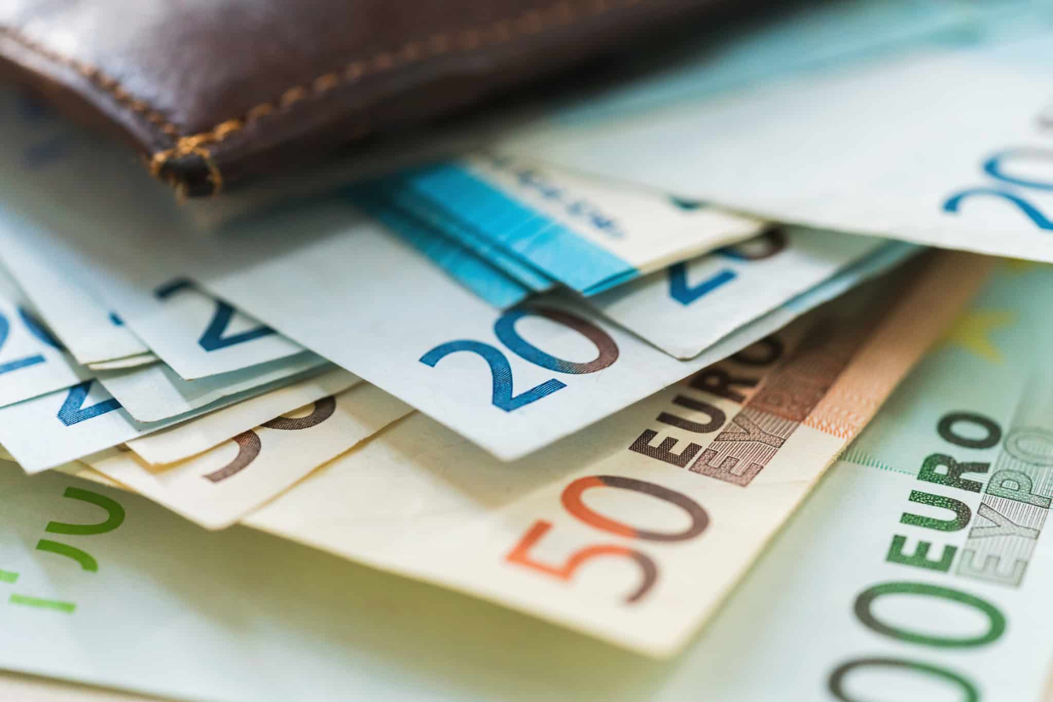 Notas de euros a saírem de uma carteira de pele castanha