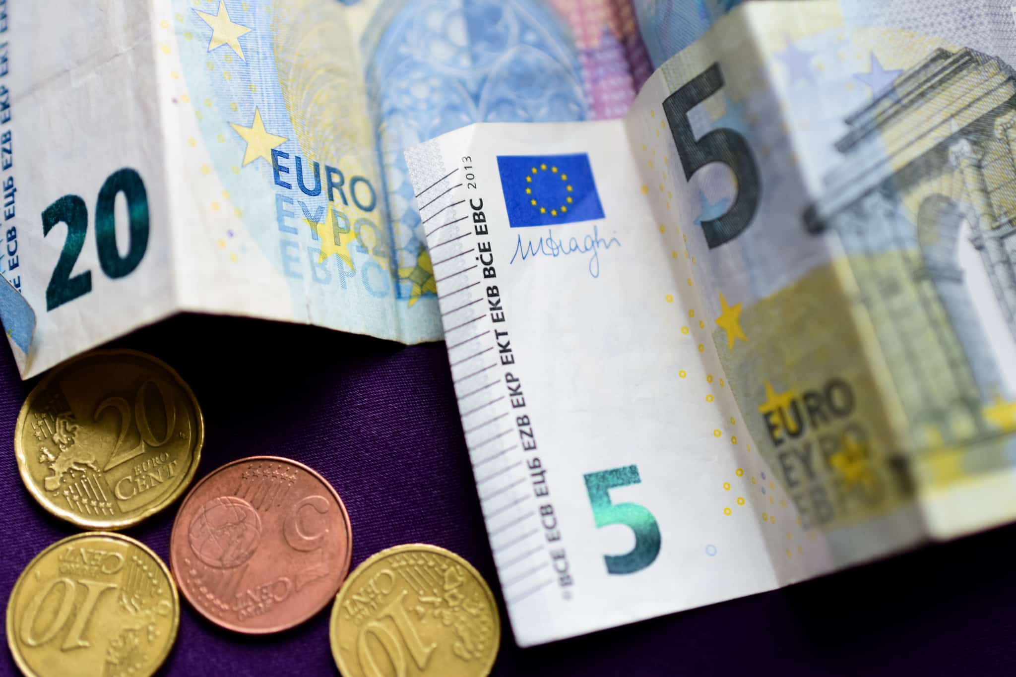 notas e moedas de euro em cima de uma mesa preparados para serem depositados numa conta poupança
