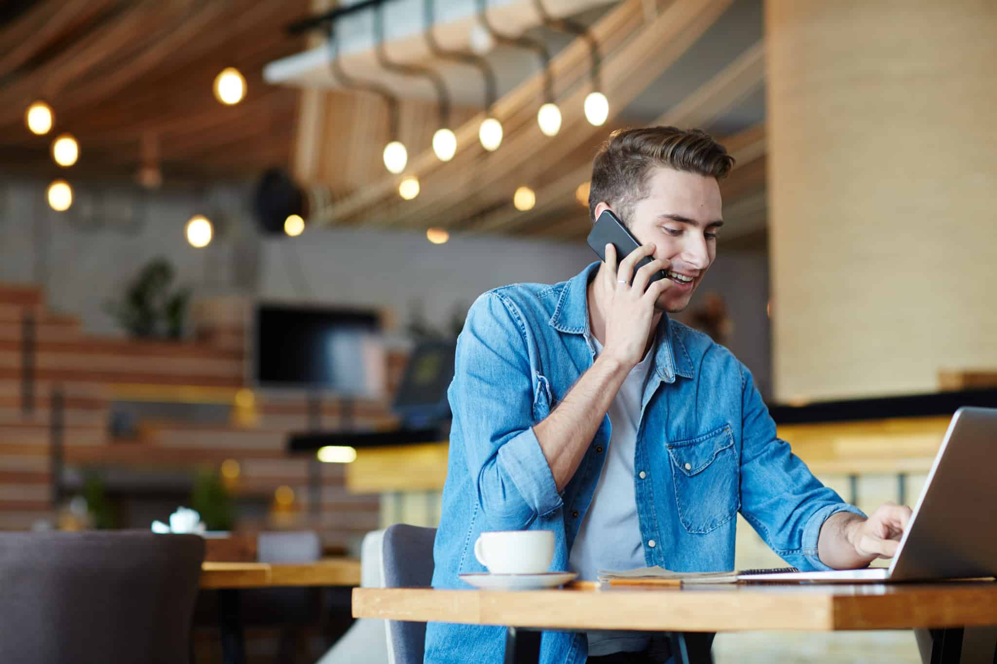 jovem rapaz freelancer trabalha num café com um ar bem disposto e dinâmico