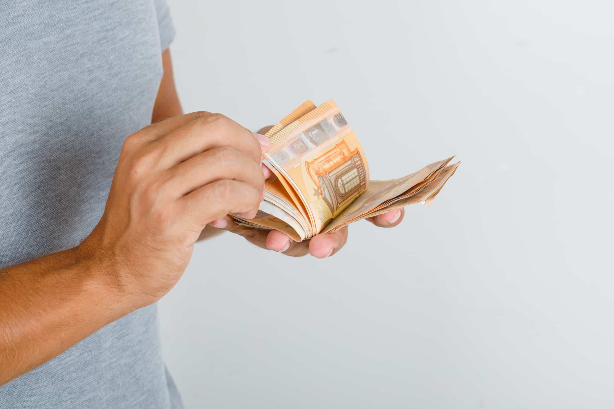 mãos de um jovem a desfolhar molho de notas de 50 euros, contando o seu subsídio de férias