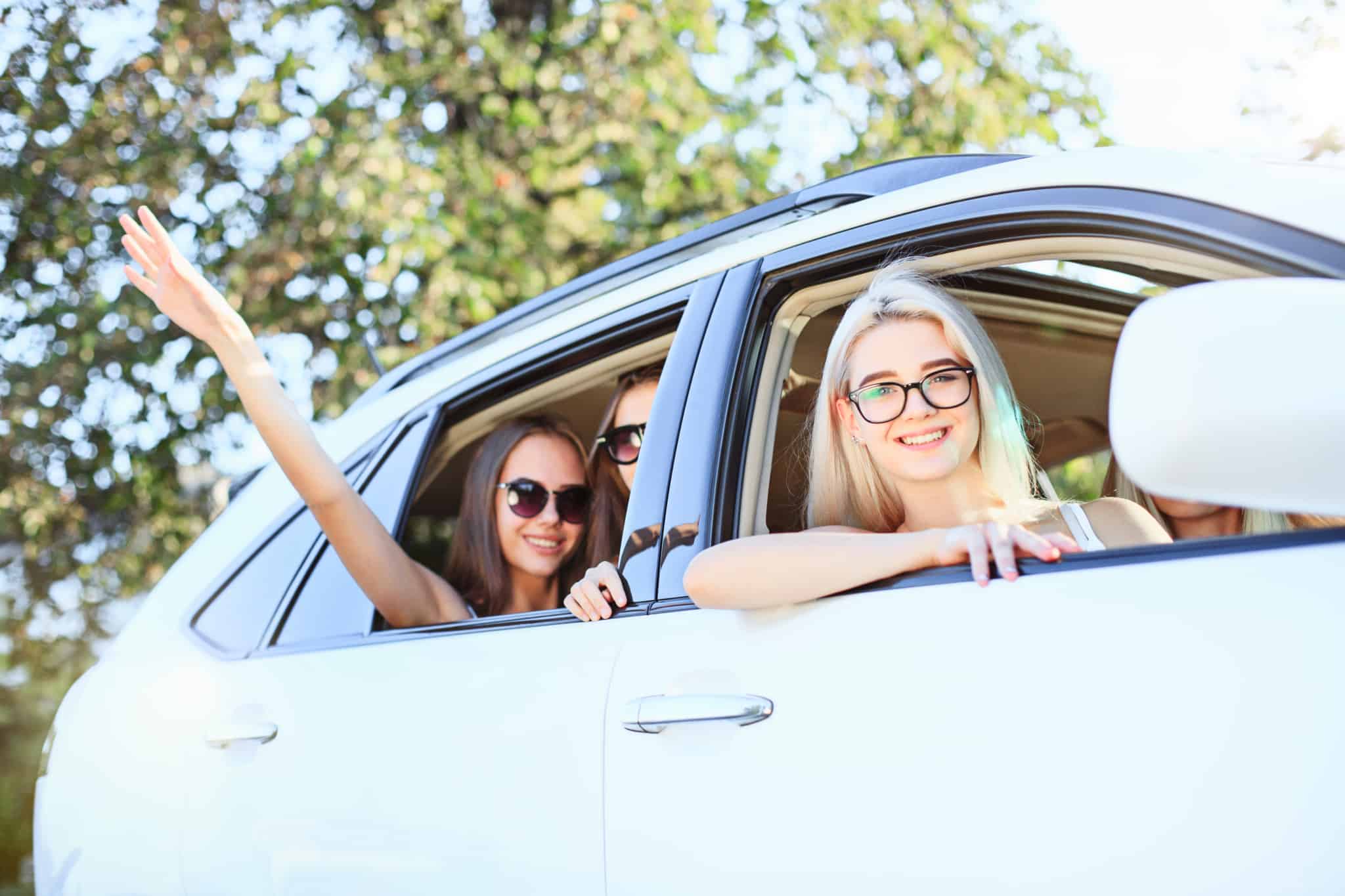jovens mulheres, muito sorridentes, á janela do carro que estão a aprtilhar, a forma sustentável de se deslocar