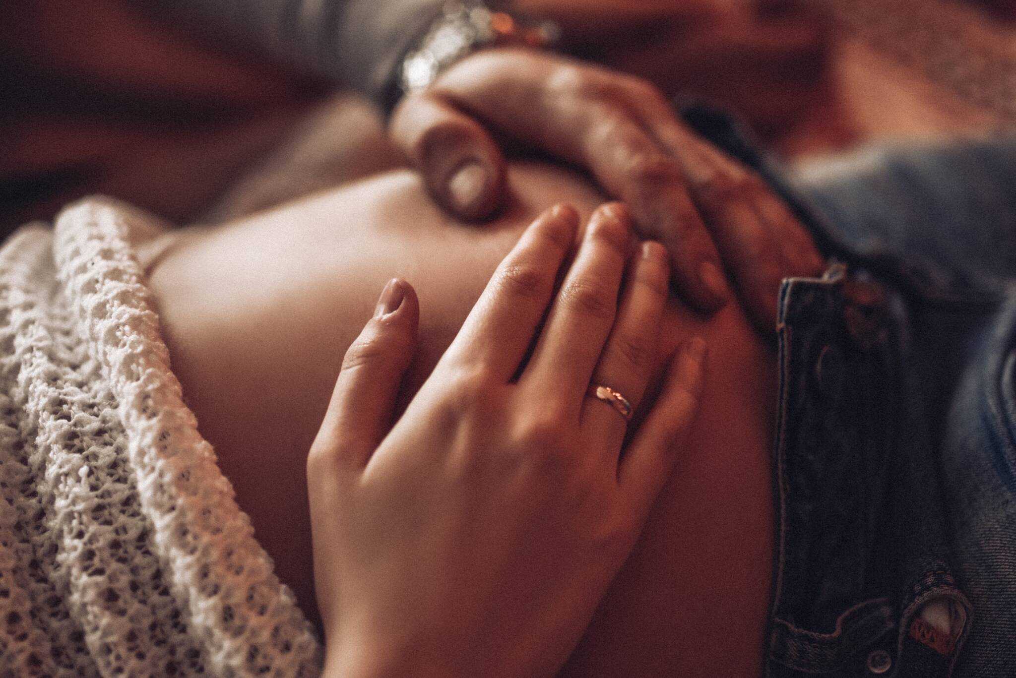 mãos de homem e mulher acariciam a barriga de grávida, tratando-se de um casal que, caso aconteça algum problema, tem acesso ao subsídio por interrupção da gravidez