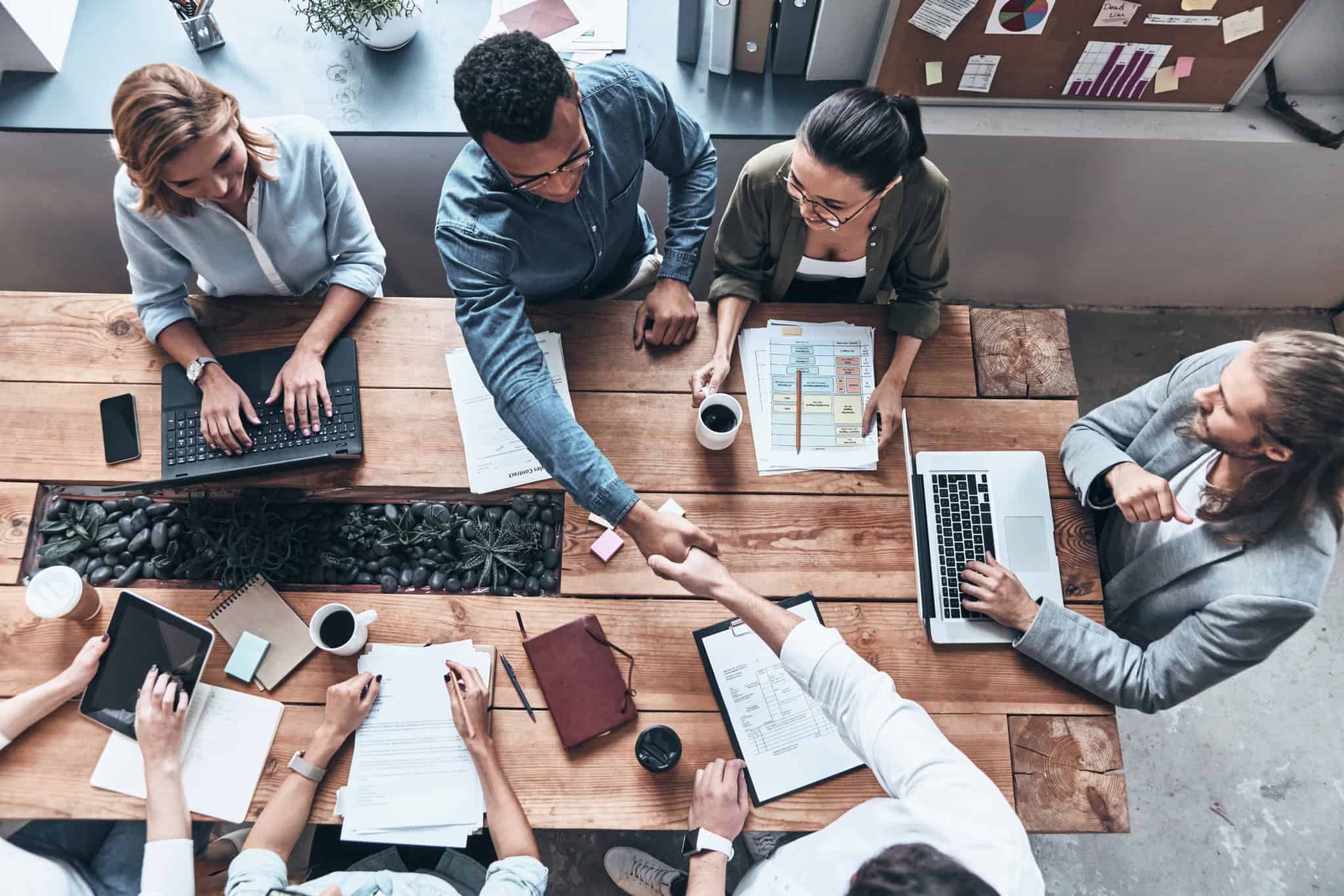 Várias pessoas sentadas a uma mesa, numa reunião de trabalho, onde é assinado um acordo