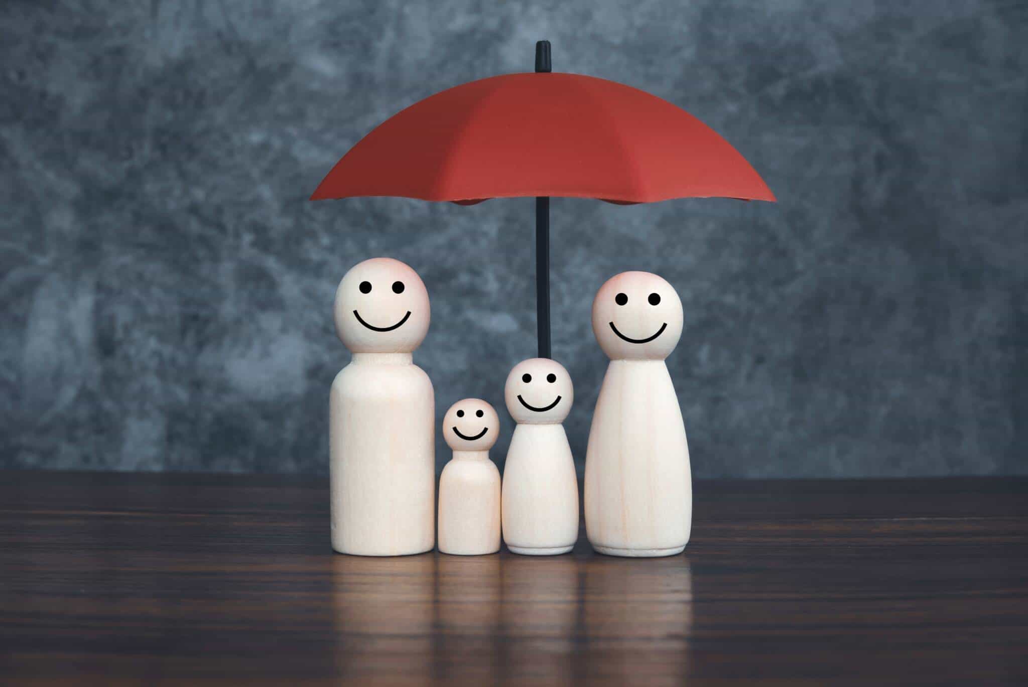 produção fotográfica ilustra o tema seguro de visa e os erros a evitar com quatro pequenos peões brancos, simbolizando a família de pai, mãe e dois filhos crianças, sob a proteção de um chapéu de chuva vermelho