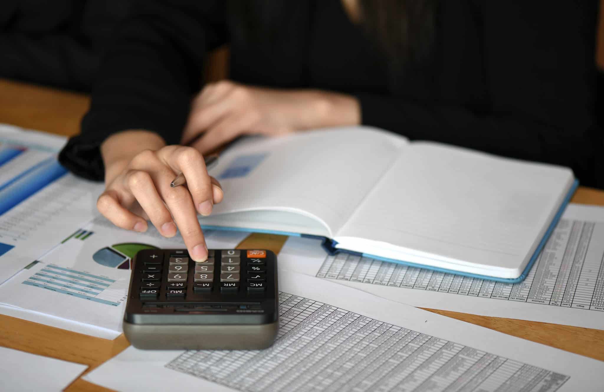 comissões bancárias que pode evitar ilustradas pela consulta de documentos, junto de uma calculadora, feita pela mão de uma jovem