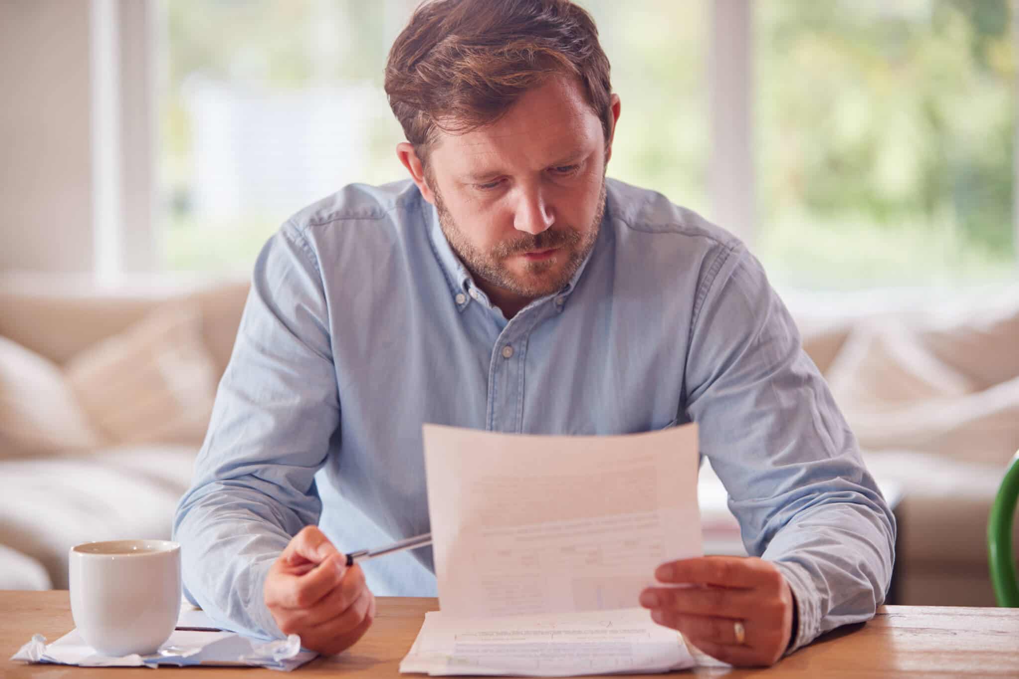 home m de meia idade, com uma cara de grande preocupação, analisa documentos para tentar reverter a sua situação de desemprego longa duração