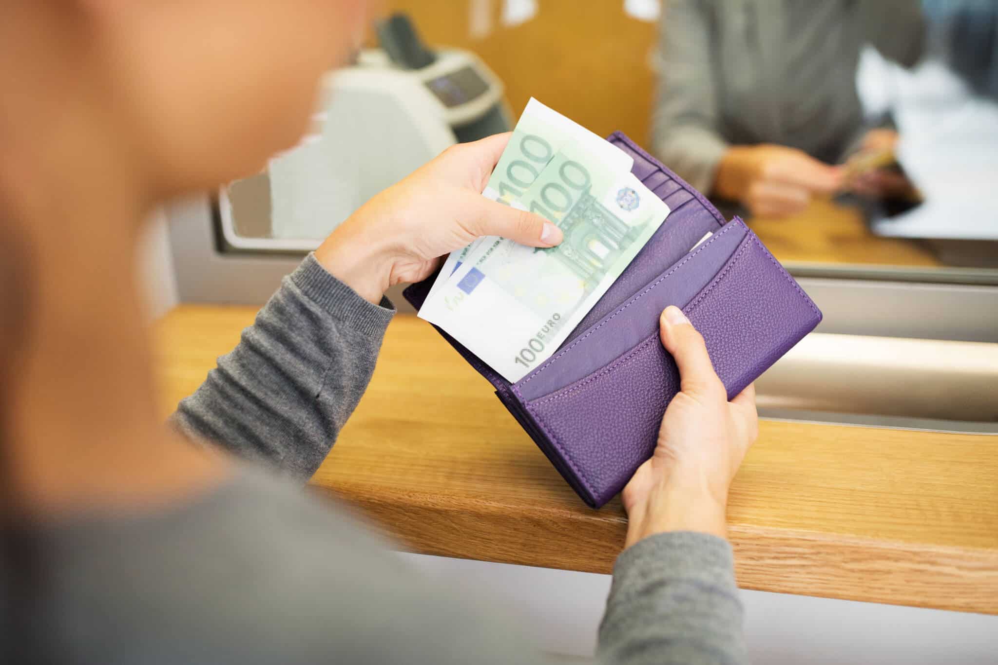 Mulher a segurar carteira com duas notas de 100 euros